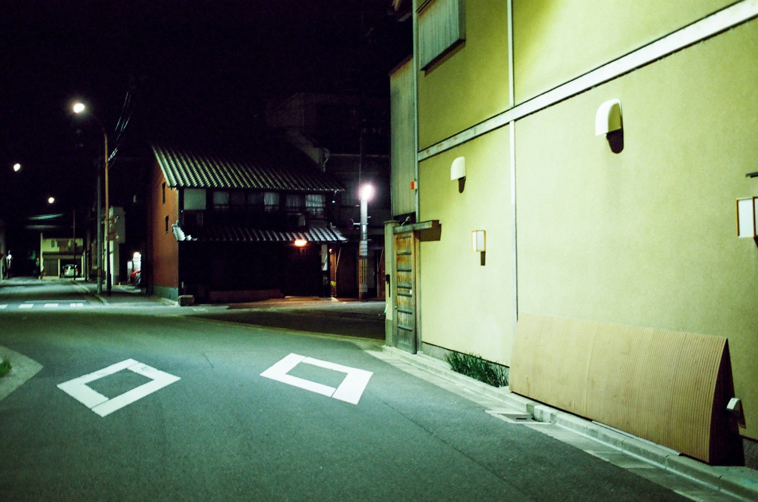 Escena de esquina de calle nocturna con carretera tranquila y edificios