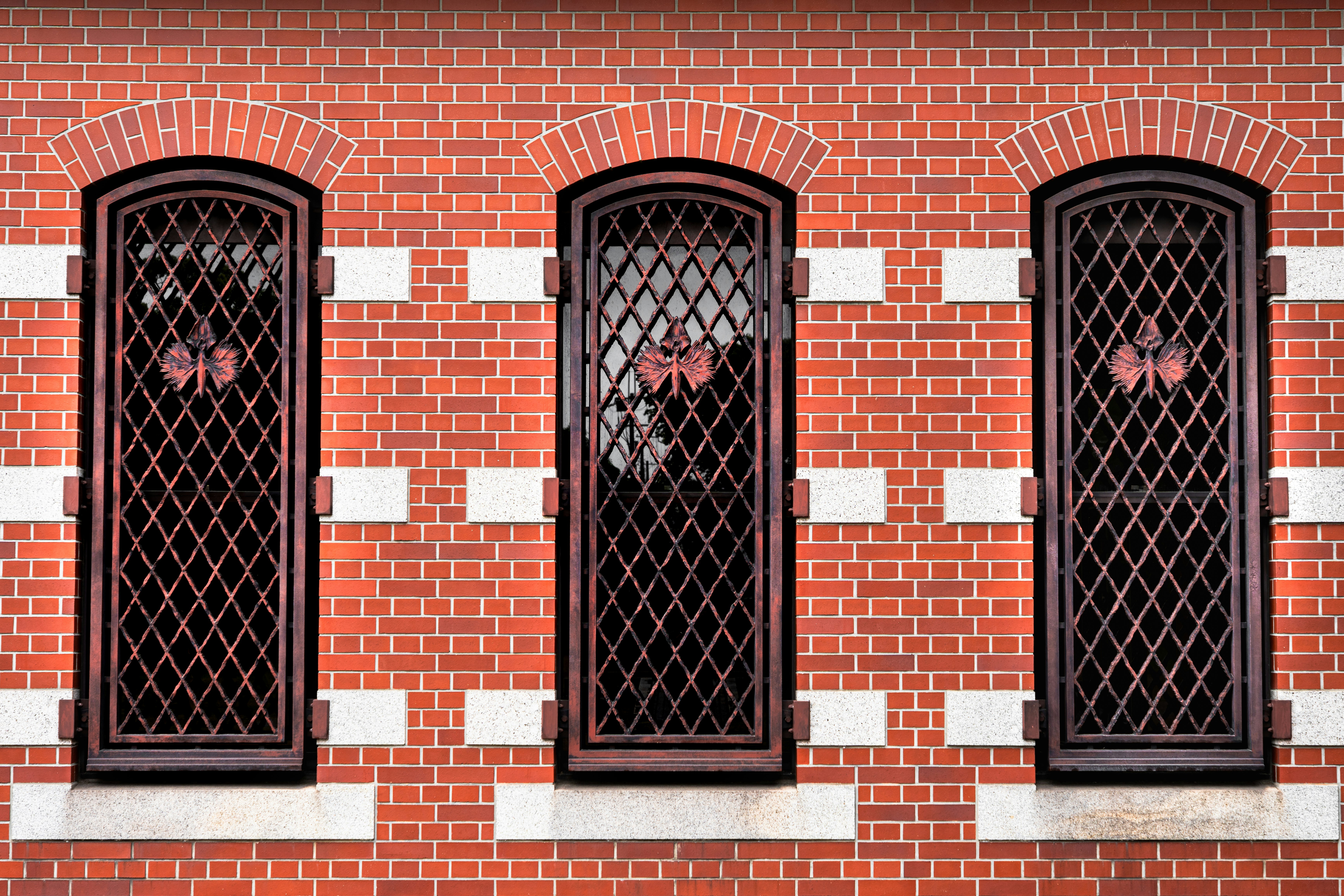 Portes grillagées alignées sur un mur en briques rouges
