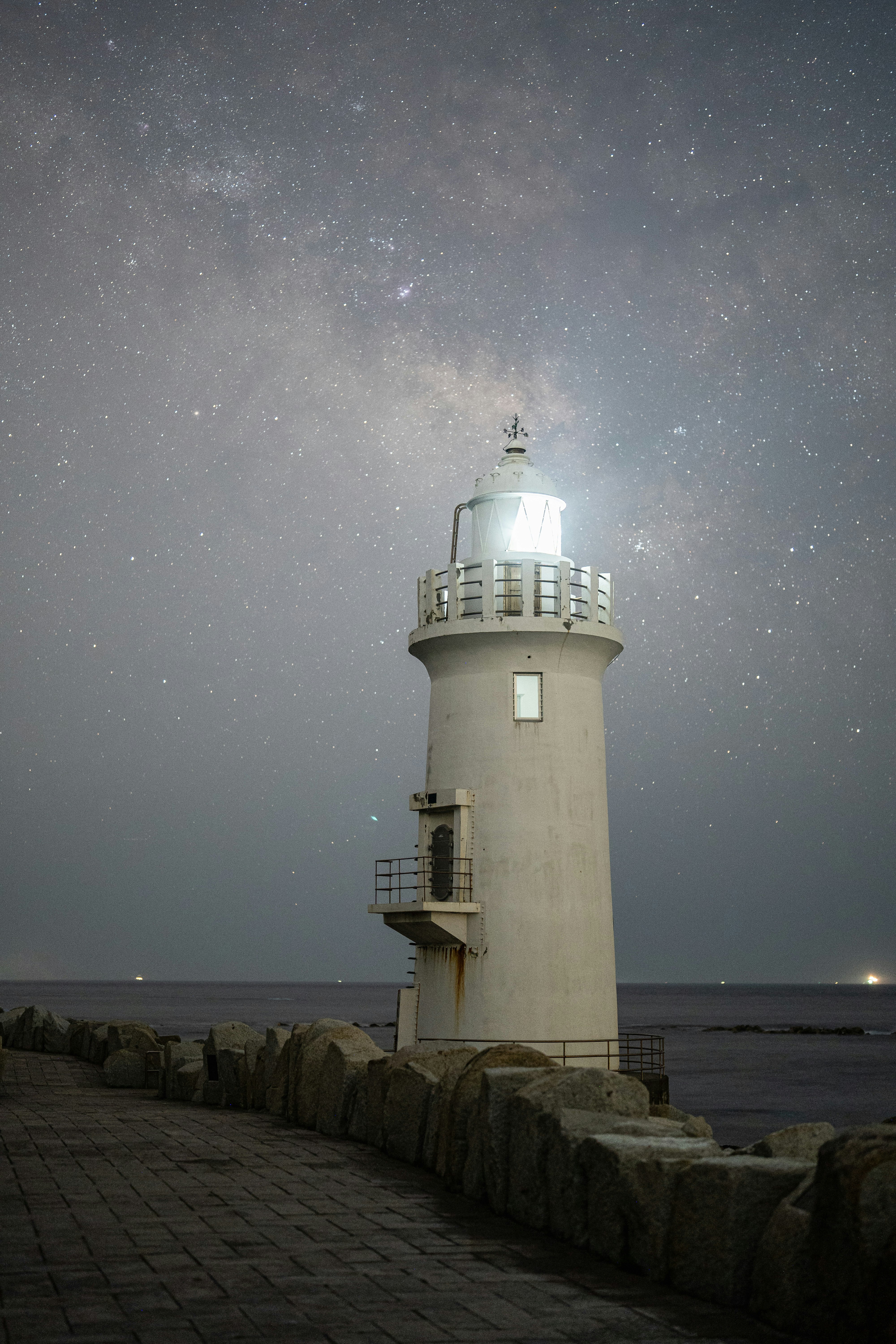 夜晚防波堤上的燈塔與星空