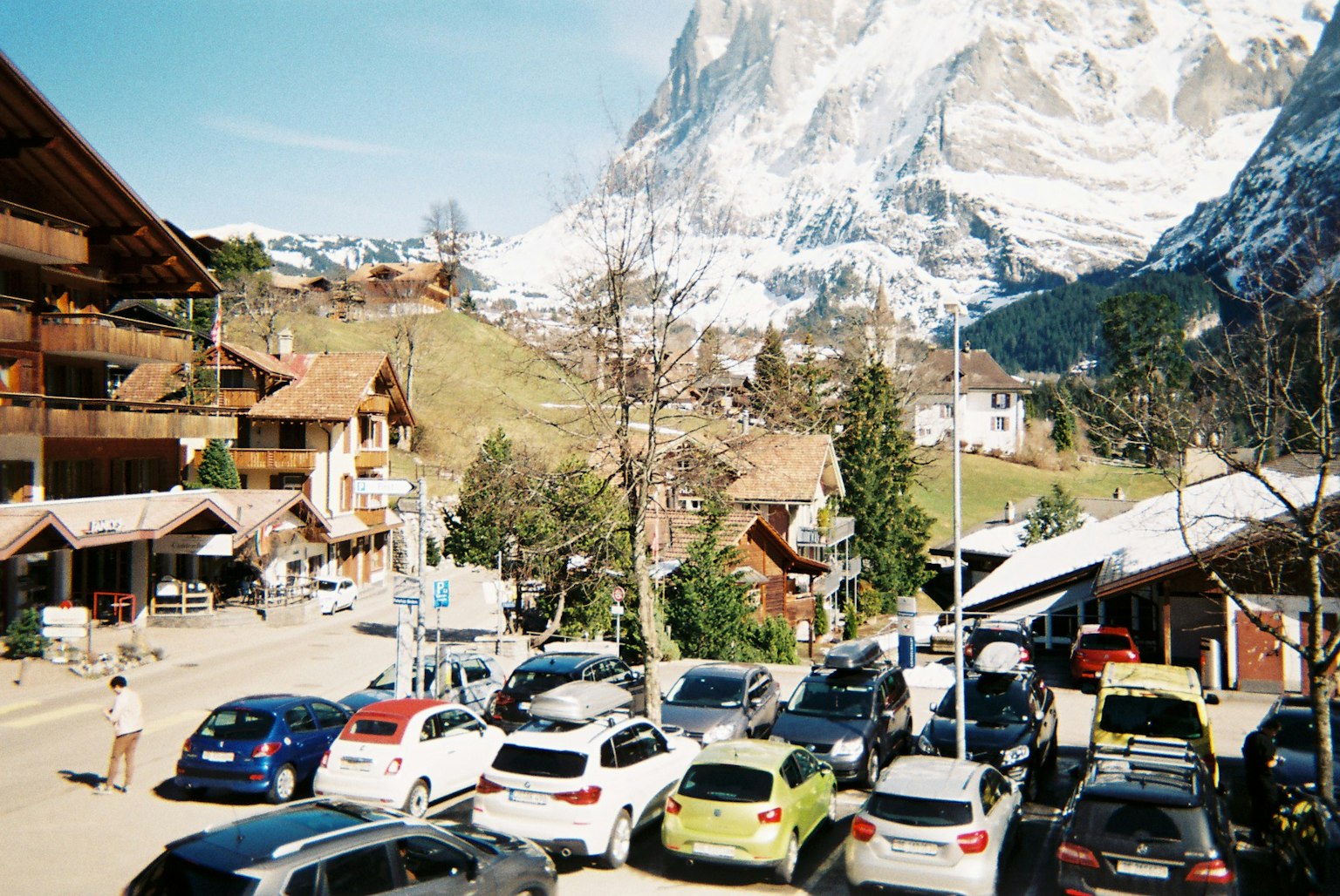 Vista panoramica di un villaggio svizzero circondato da montagne diverse auto parcheggiate in un'area