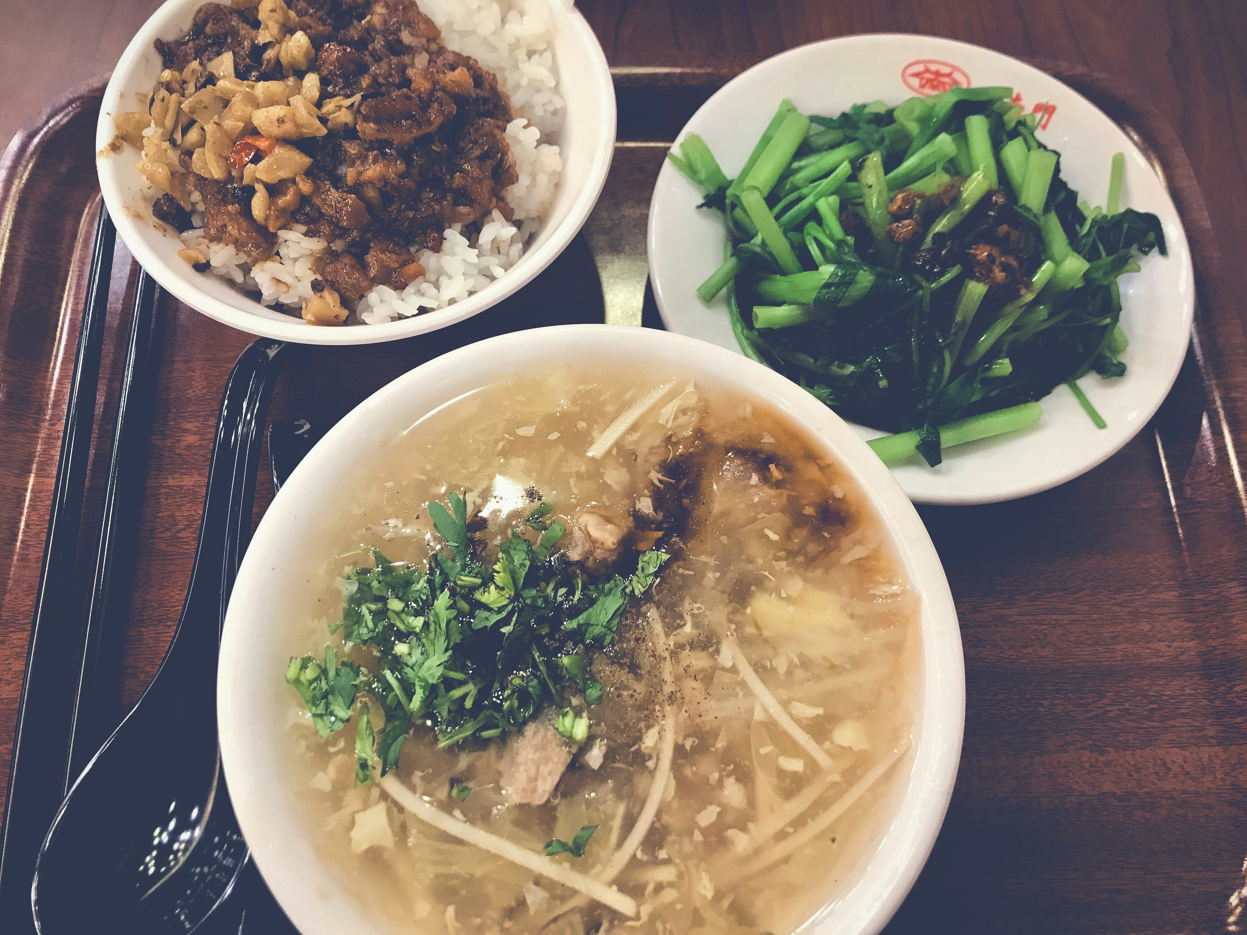 一个托盘上放着一碗汤、一碗蒸米饭和一盘炒青菜