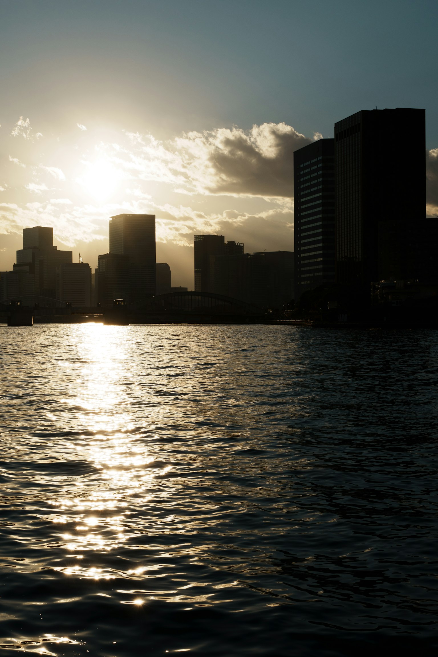 Silhouette della città al tramonto con riflessi sull'acqua