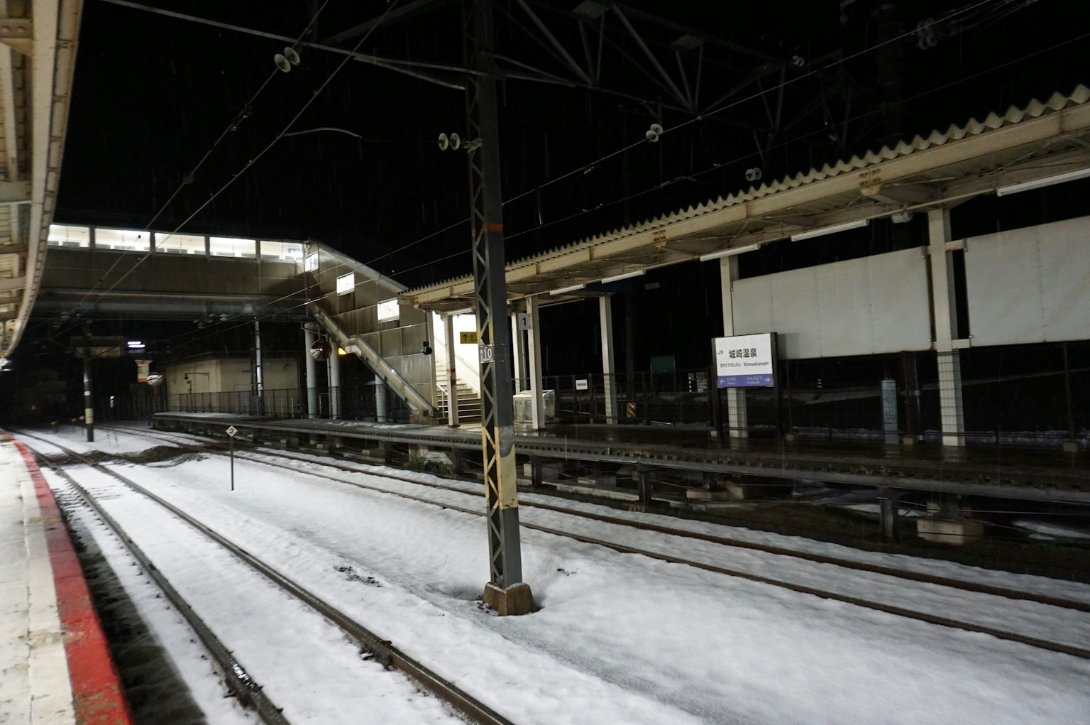 Plateforme de gare et voies recouvertes de neige