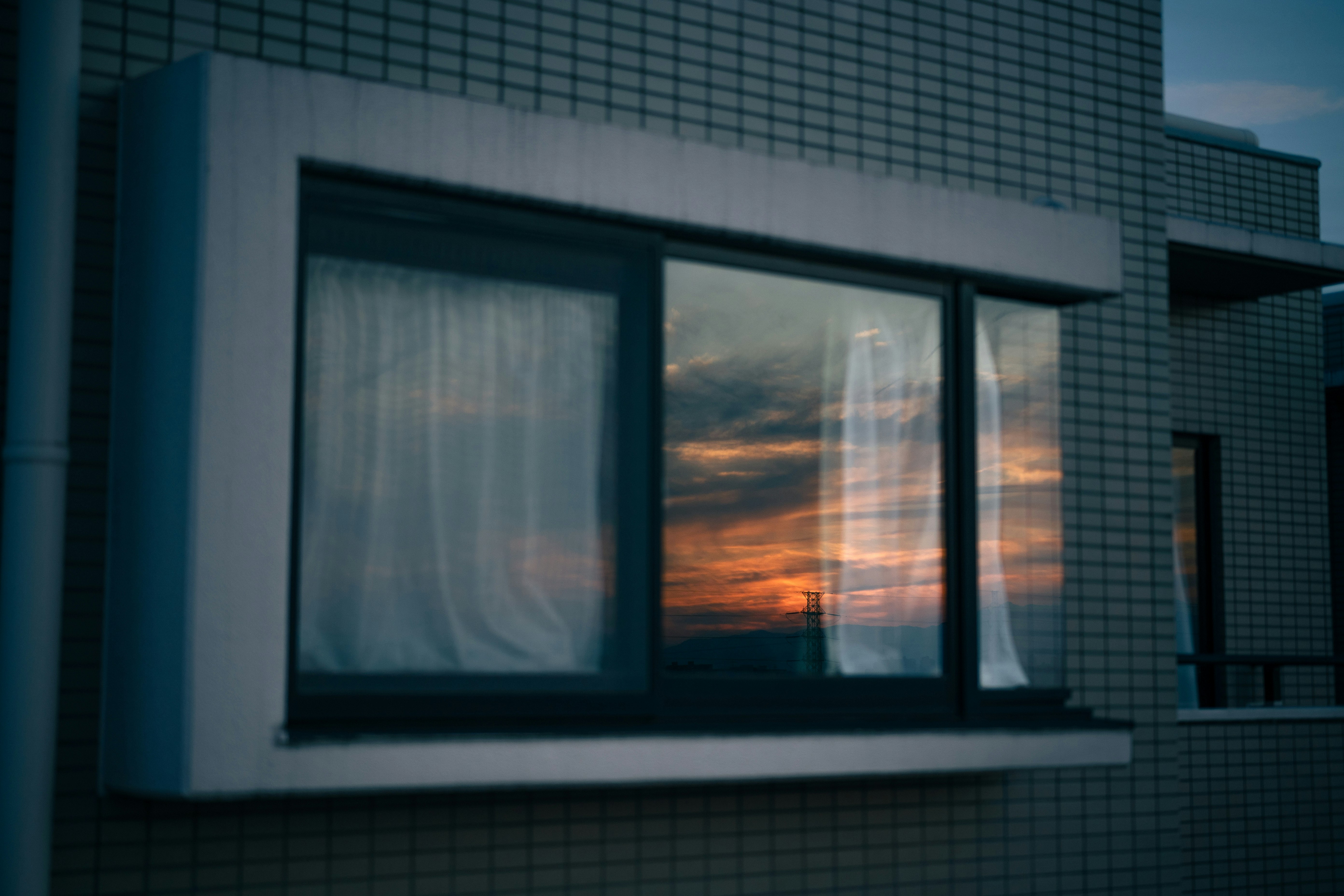 fachada de un edificio con reflejos del atardecer en el vidrio de la ventana