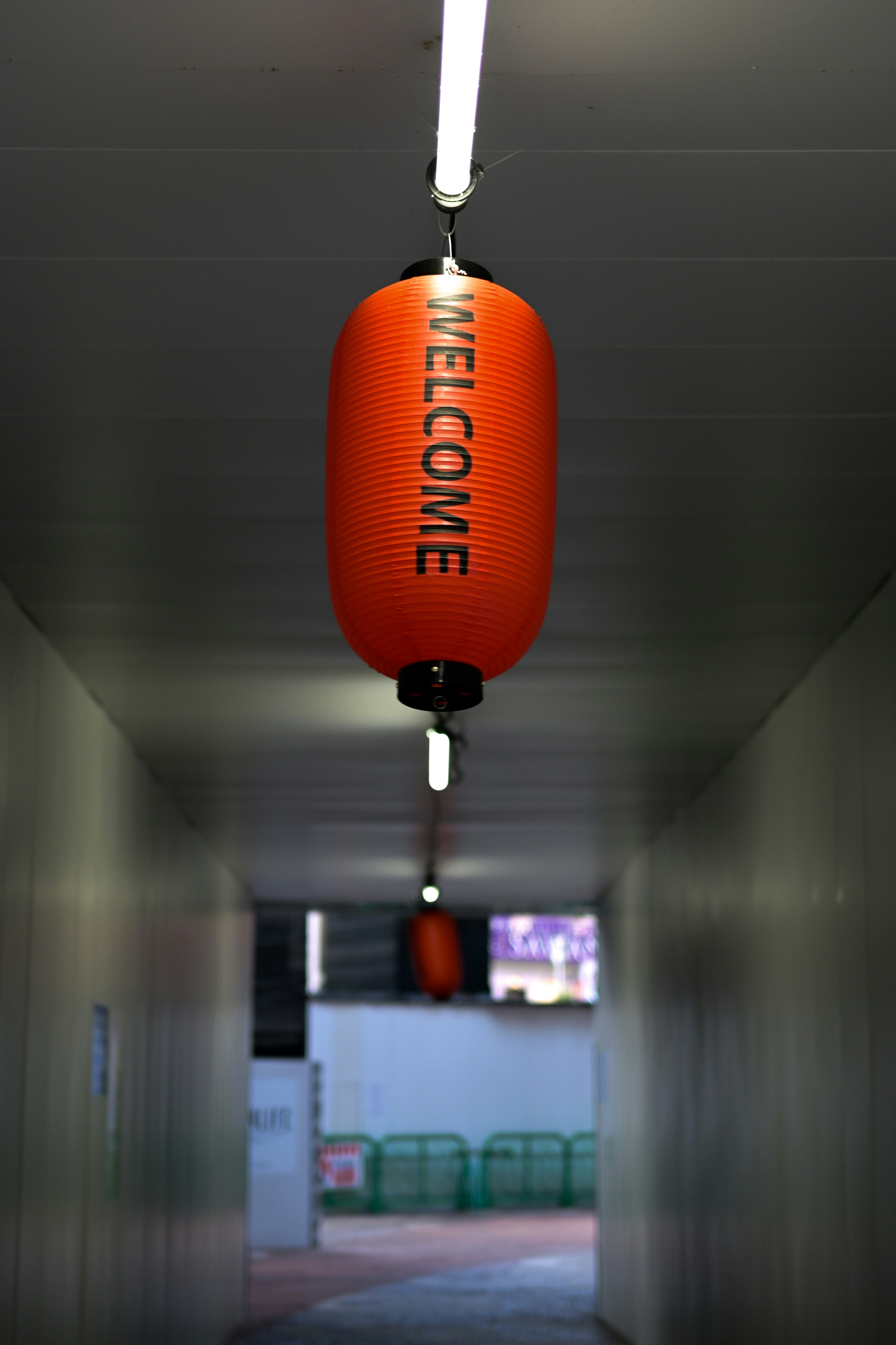 天井から吊るされたオレンジ色のメガホン型ランプのある廊下