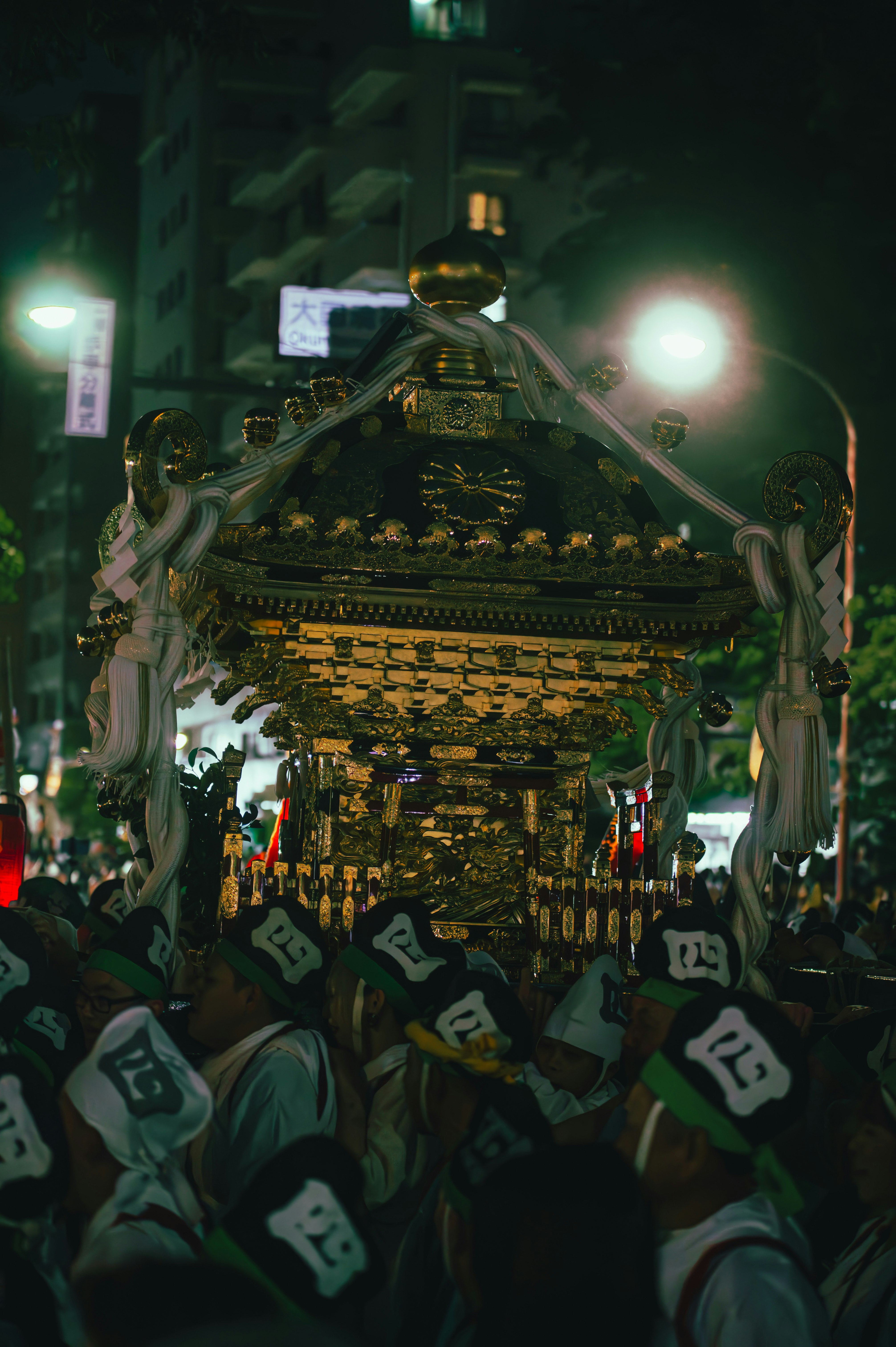 提灯と提灯飾りのある祭りの山車を見上げる夜の群衆