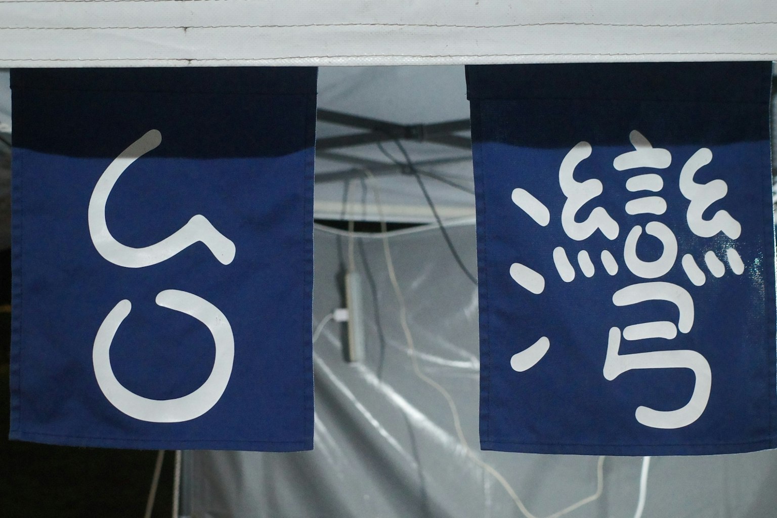 青いのれんに白い文字の看板が二つ並んでいる