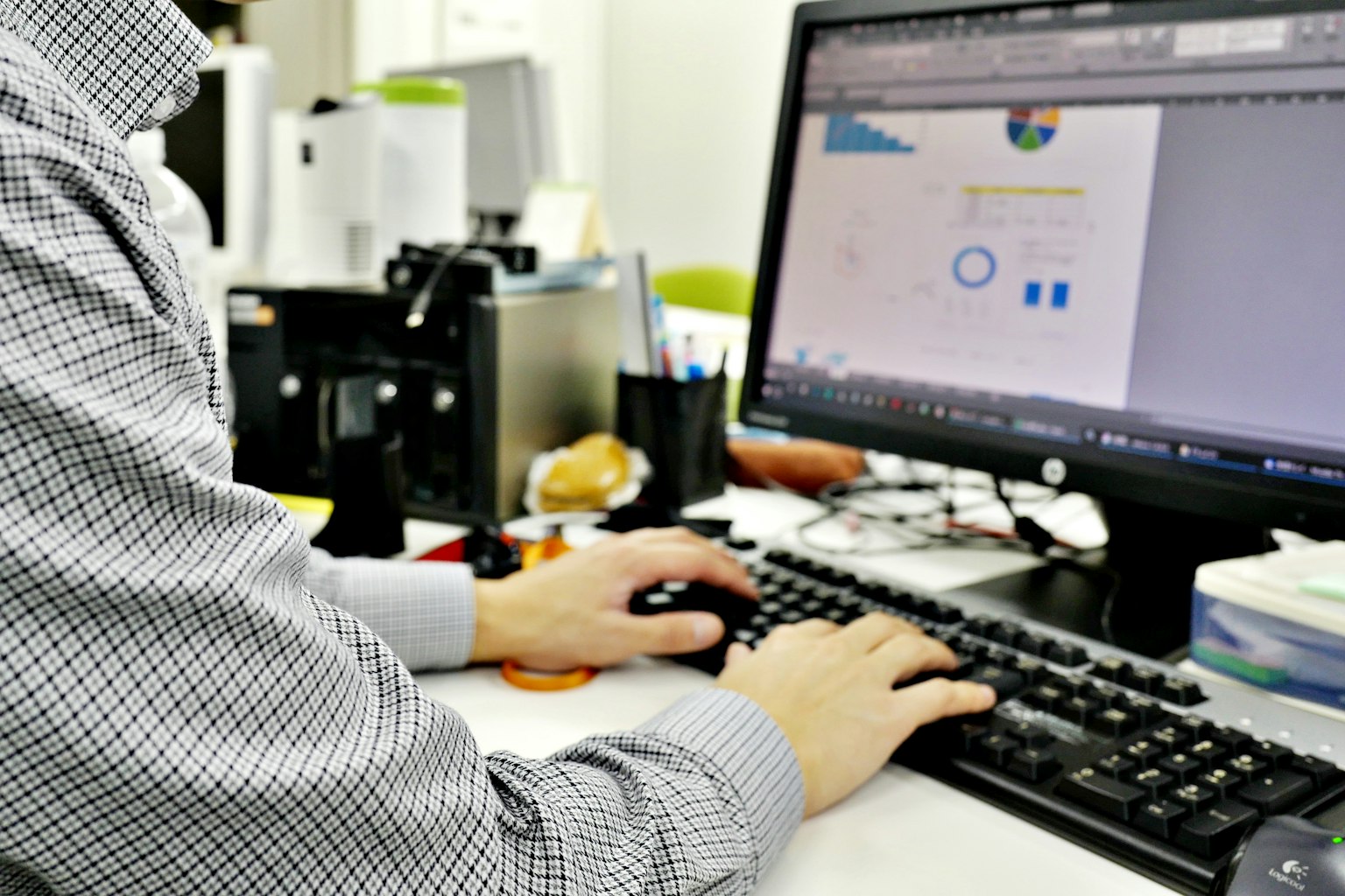Eine Männerhand auf einer Tastatur, die an einem Computer mit Grafiken und Designs arbeitet