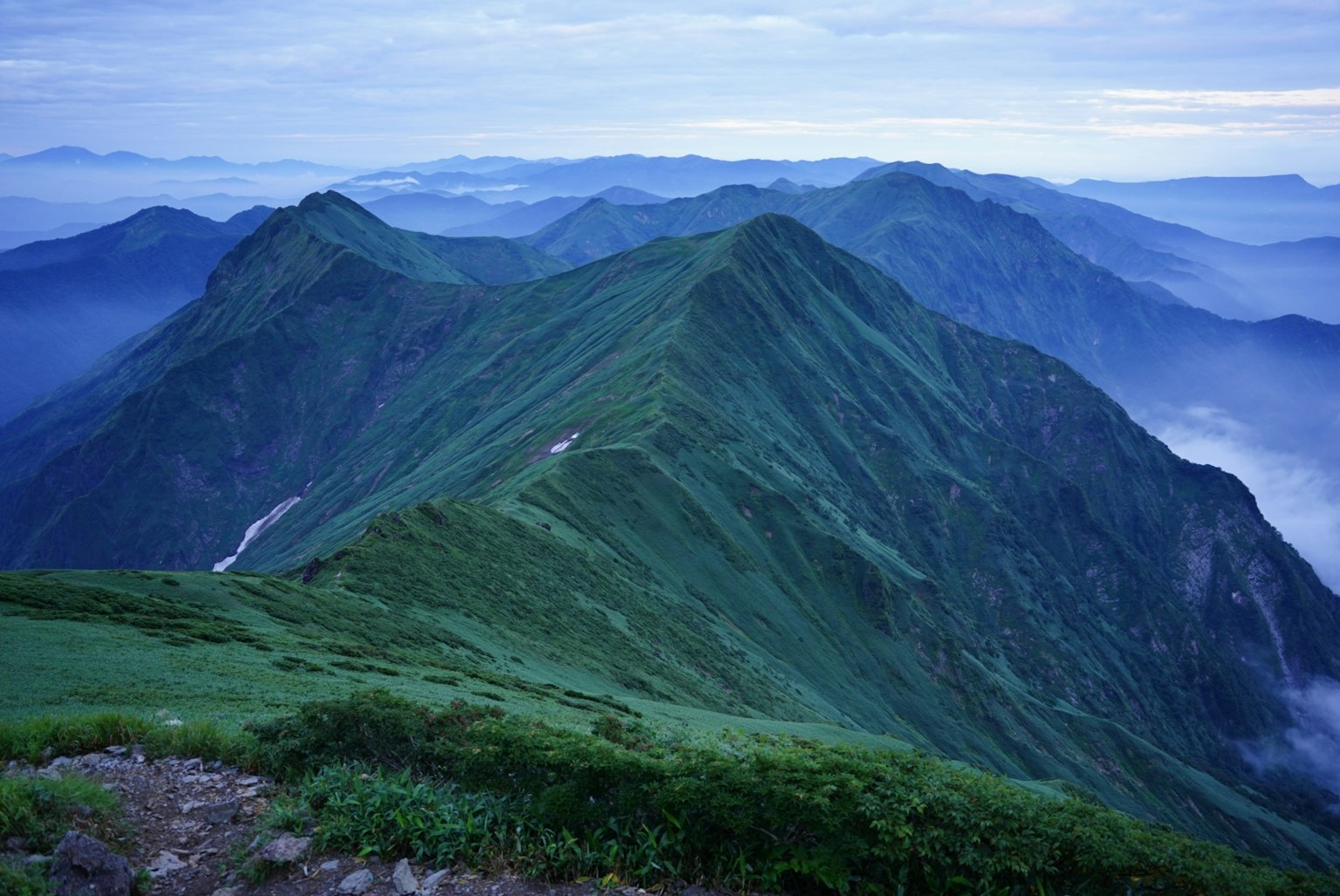Khung cảnh núi xanh với sườn đồi xanh và thung lũng sương mù