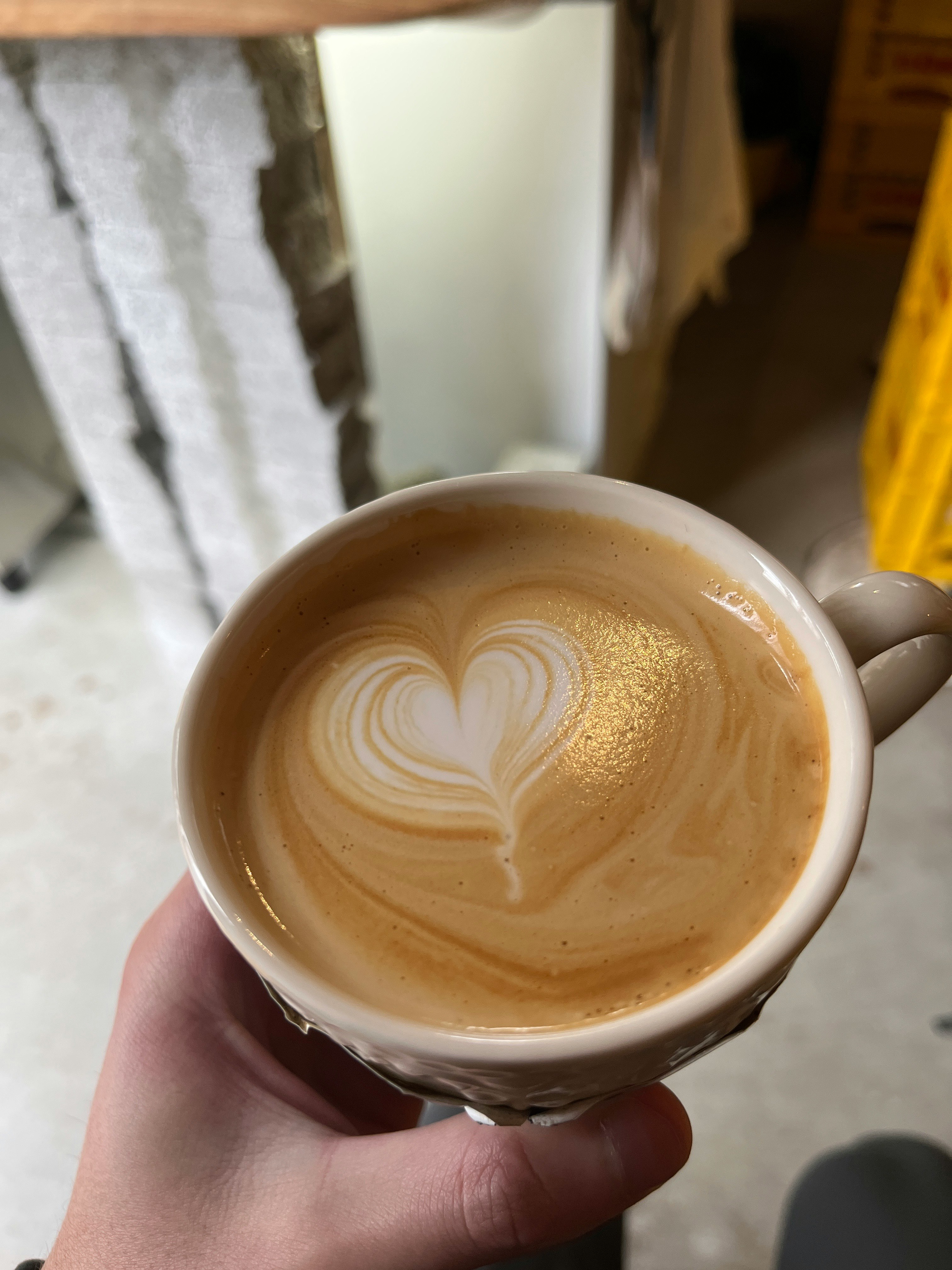 ラテアートの入ったカフェラテを手に持つカップ