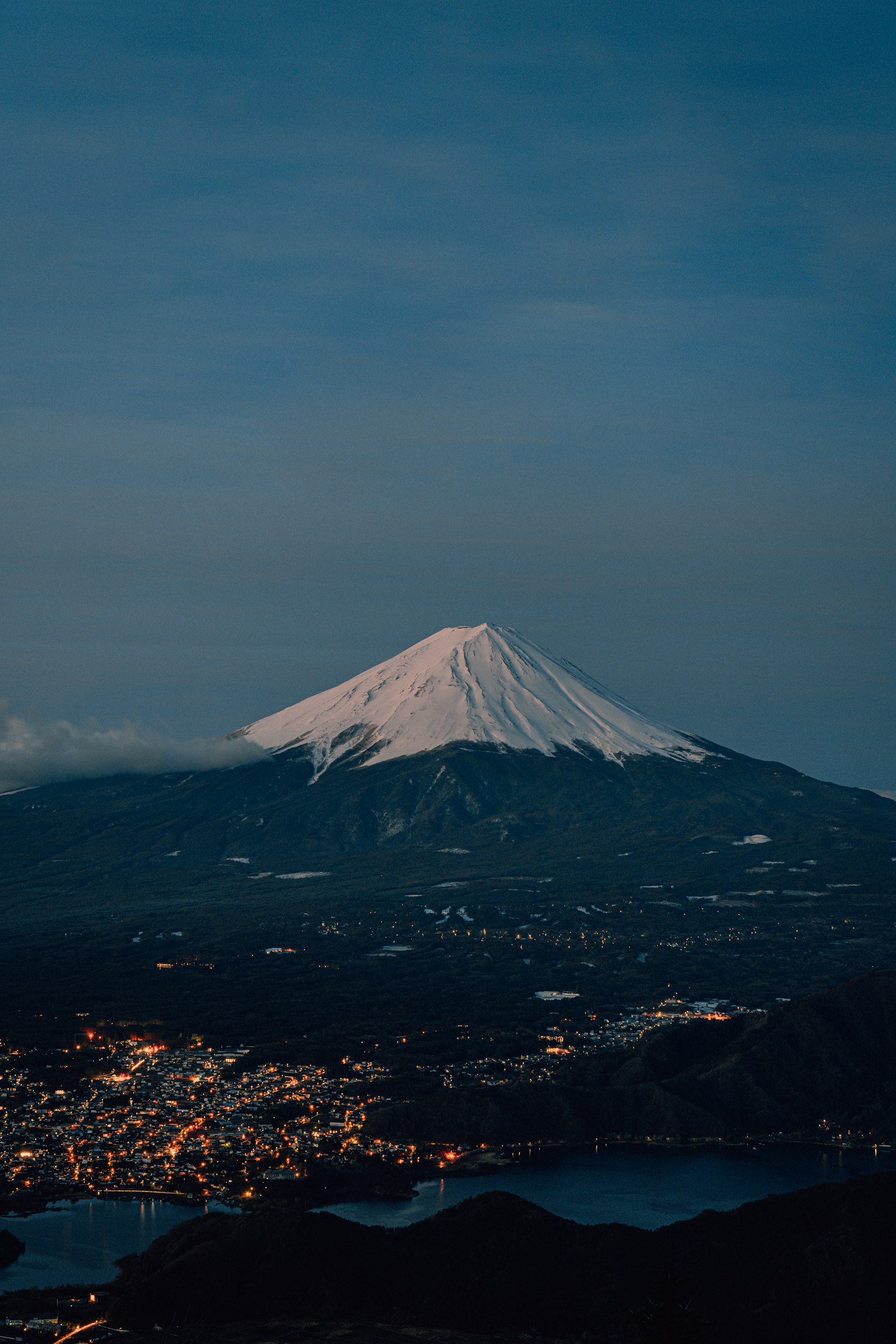Mount Fuji with snow-capped peak and surrounding town at night