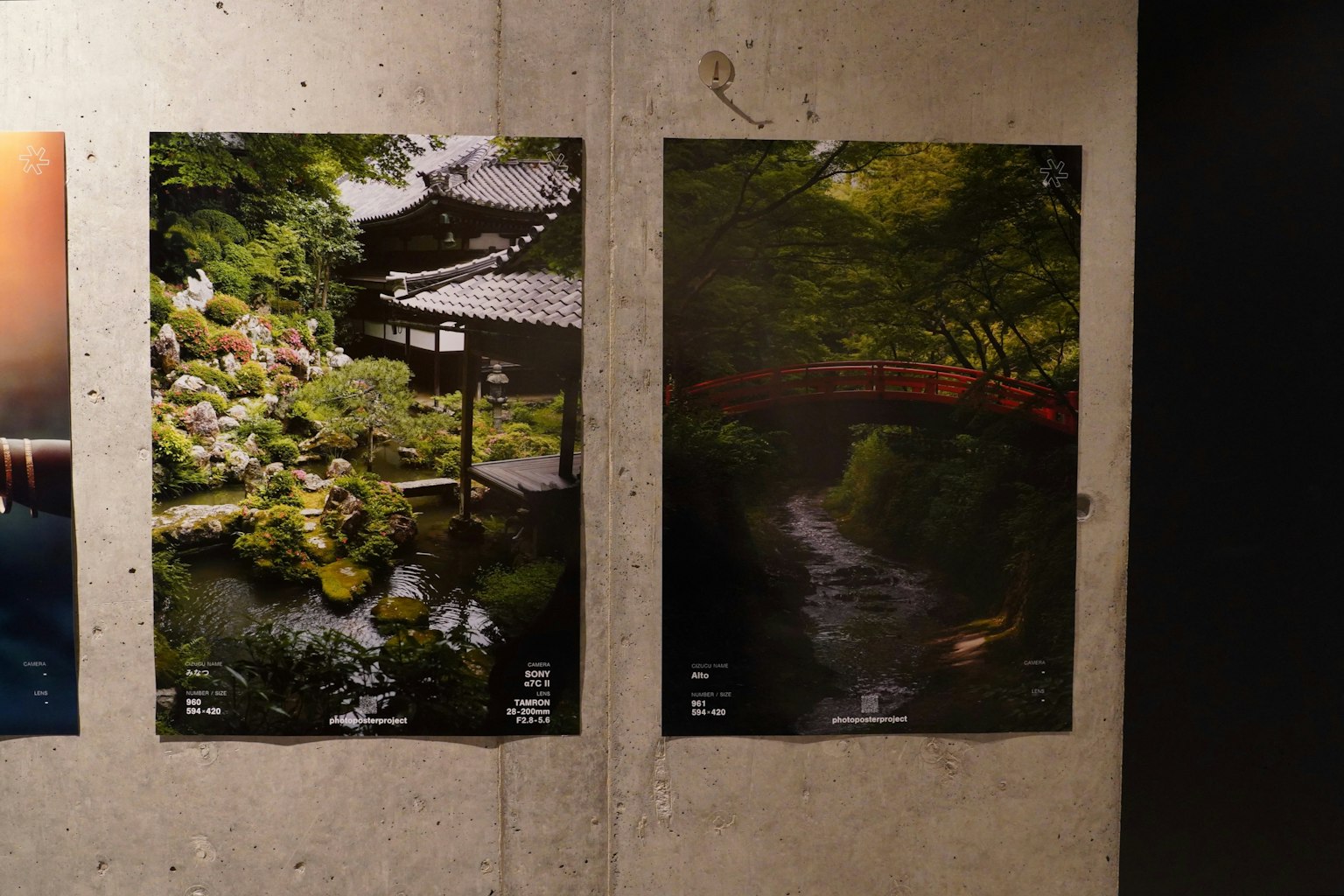 Two landscape photographs hanging on a wall One features a Japanese garden with a small bridge The other shows a tranquil water surface surrounded by greenery