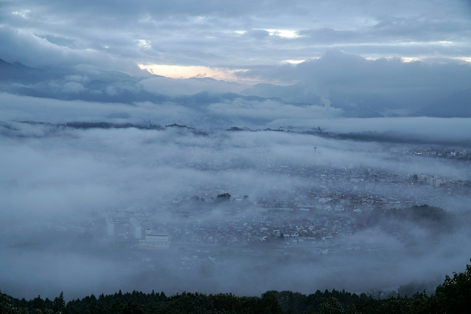 Vue aérienne d'une ville enveloppée de brouillard avec un ciel bleu et des nuages au crépuscule