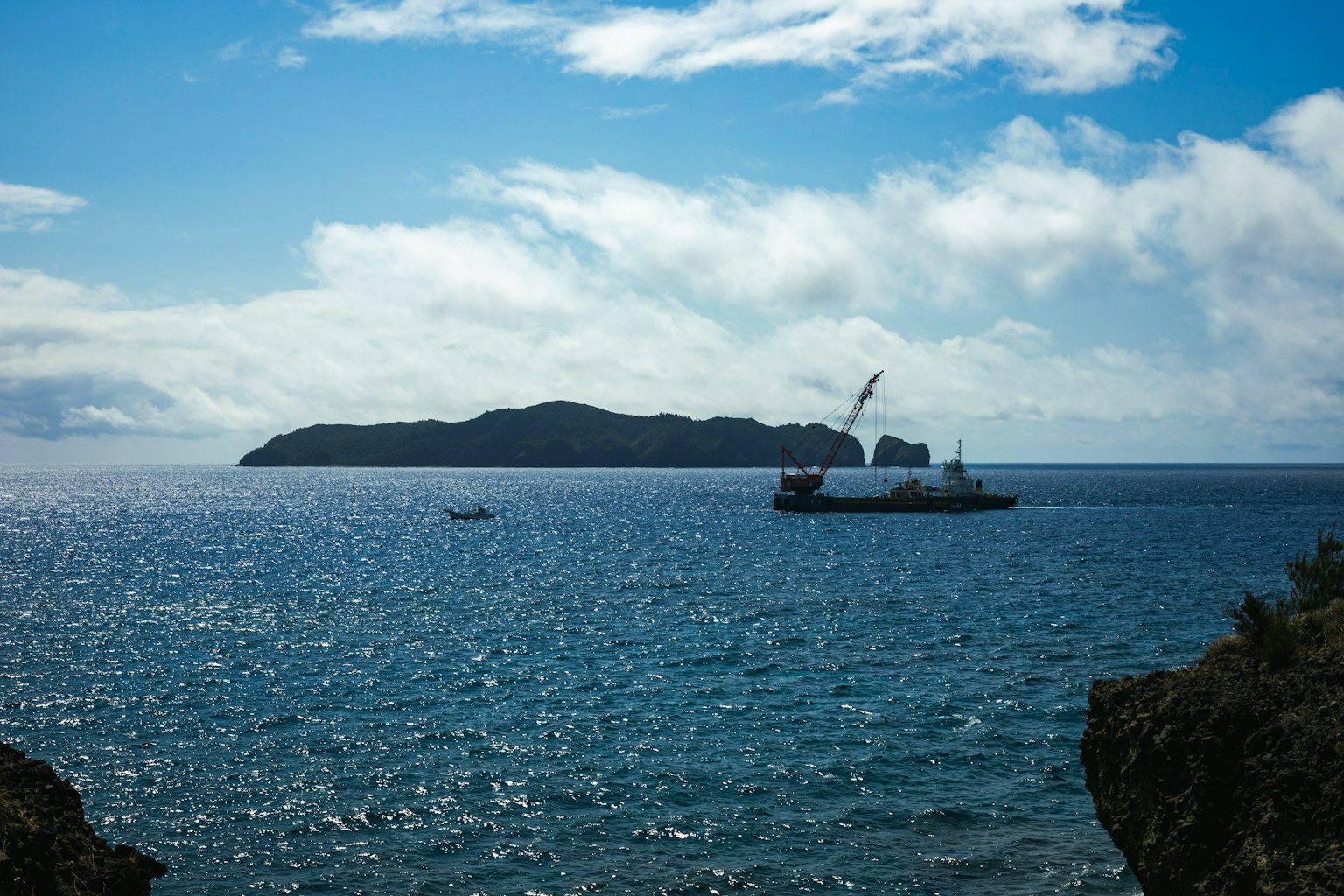 Île et bateau sur une mer bleue sous un ciel nuageux