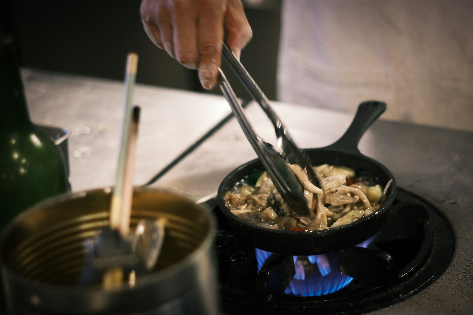 Chef che cucina ingredienti in una padella su un fornello