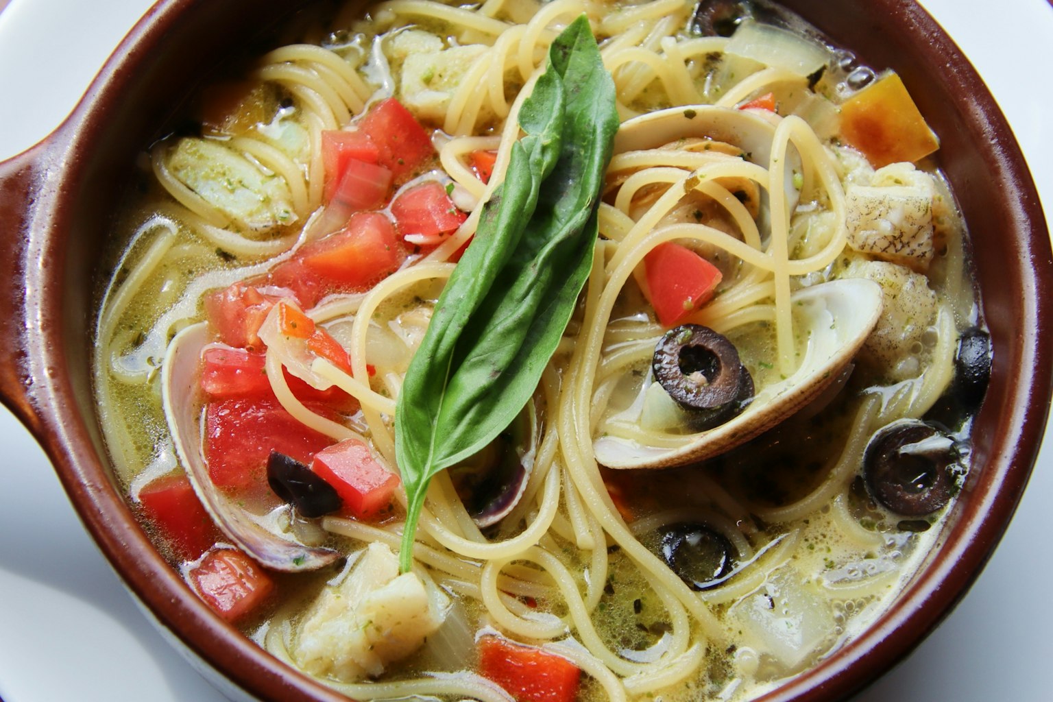 Un bol de spaghetti avec des légumes et une feuille de basilic sur le dessus