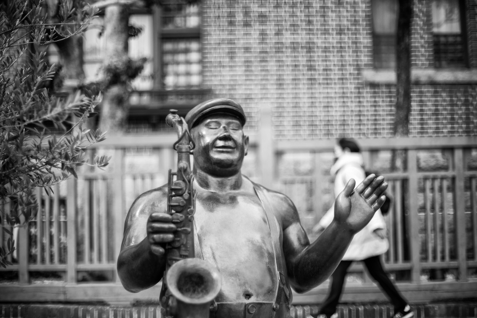 A statue of a Black man holding a saxophone stands in a park
