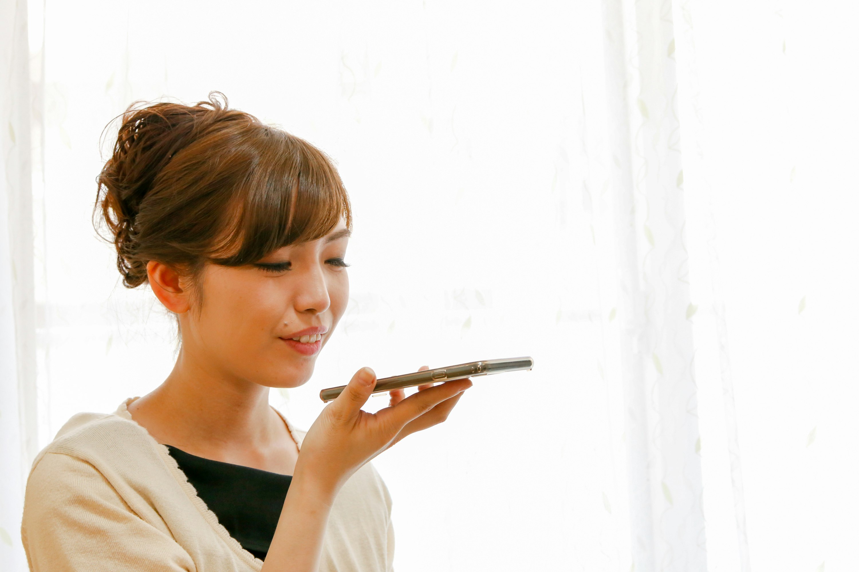 白い背景でスマホを見つめる女性