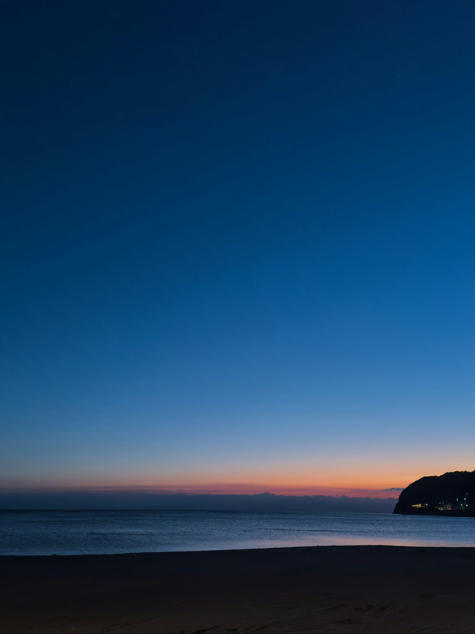 夕焼けの海と砂浜、水平線の風景