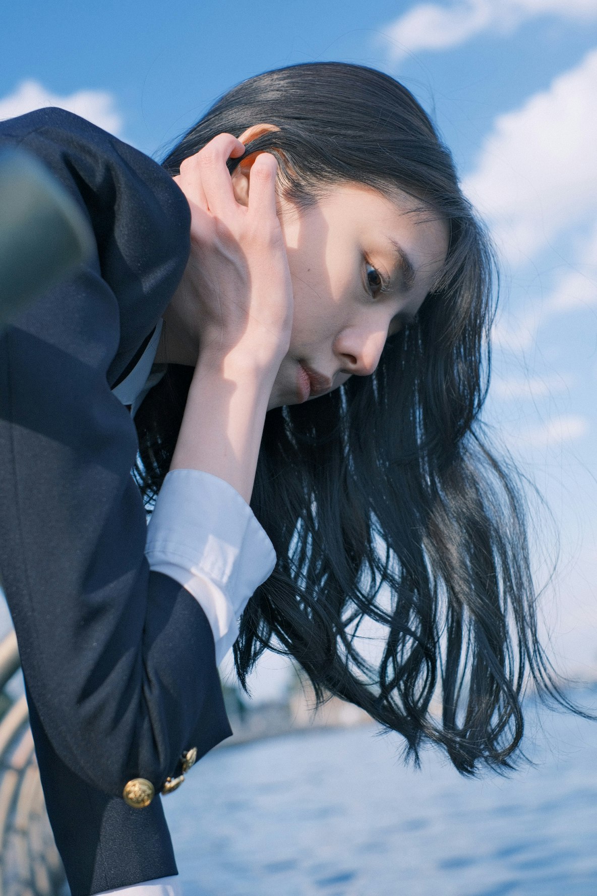 mujer con traje tocándose la oreja bajo un cielo azul