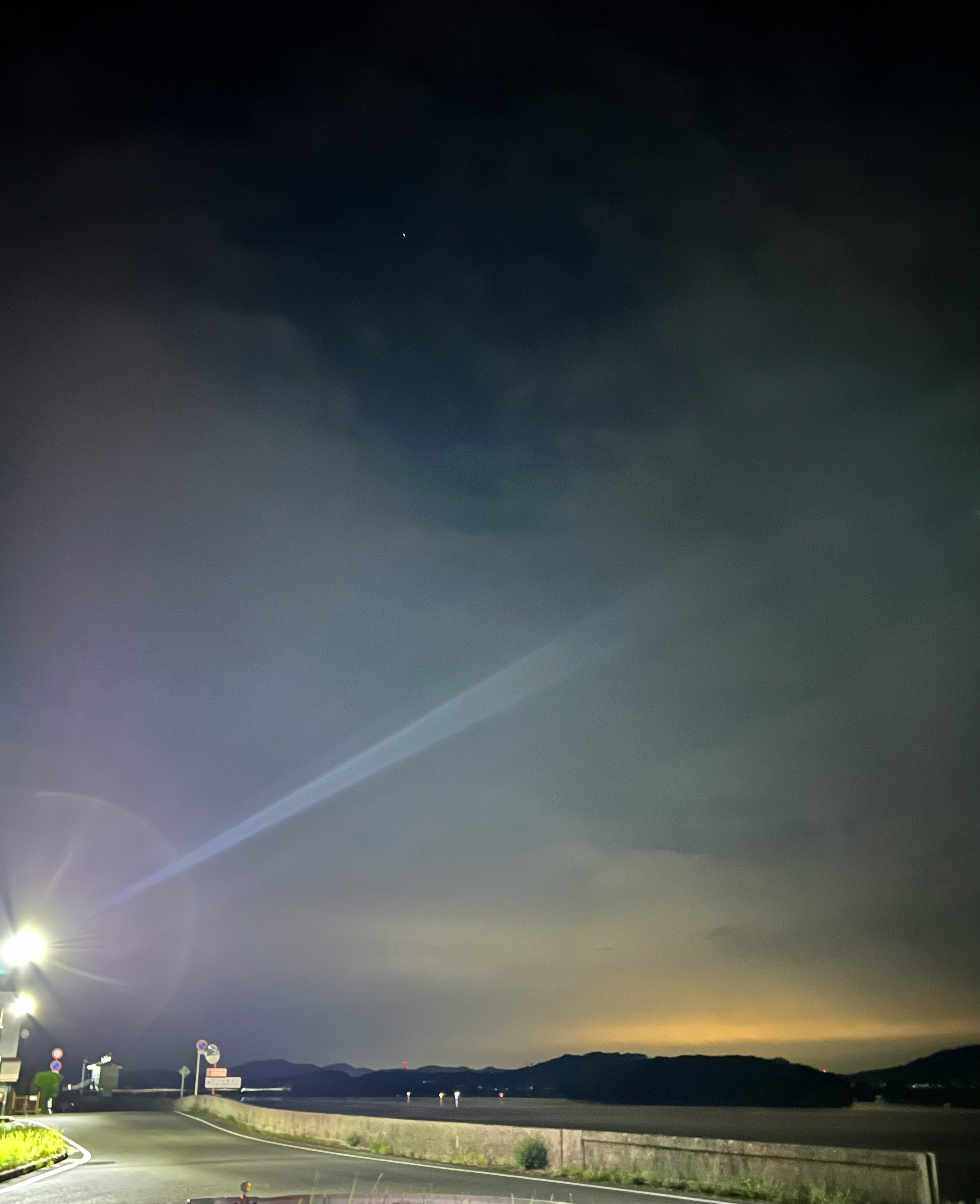 Street lights reflecting in a cloudy night sky over a road