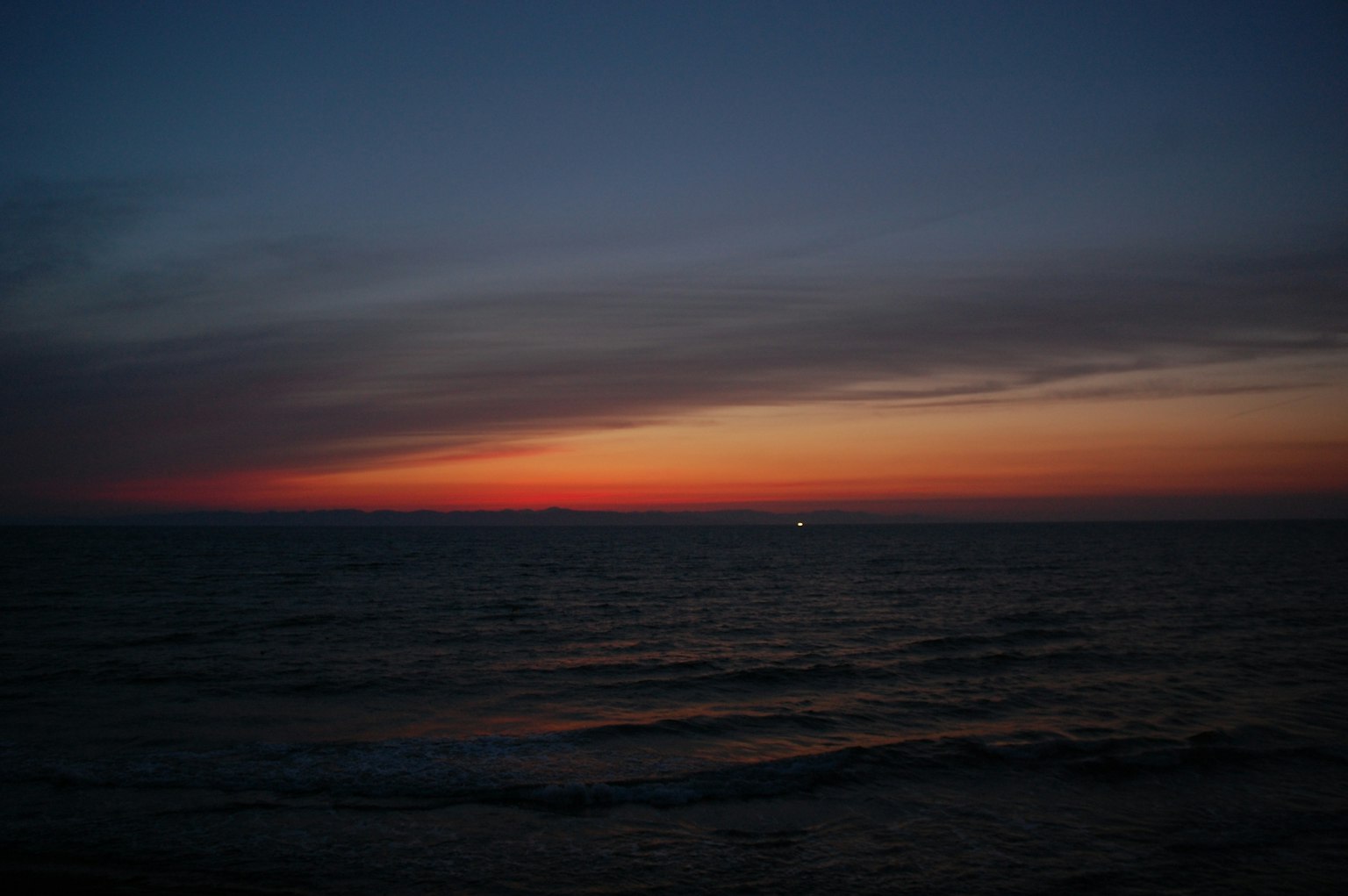 Sonnenuntergang über dem Ozean mit blauem und orangefarbenem Farbverlauf ruhige Wellen