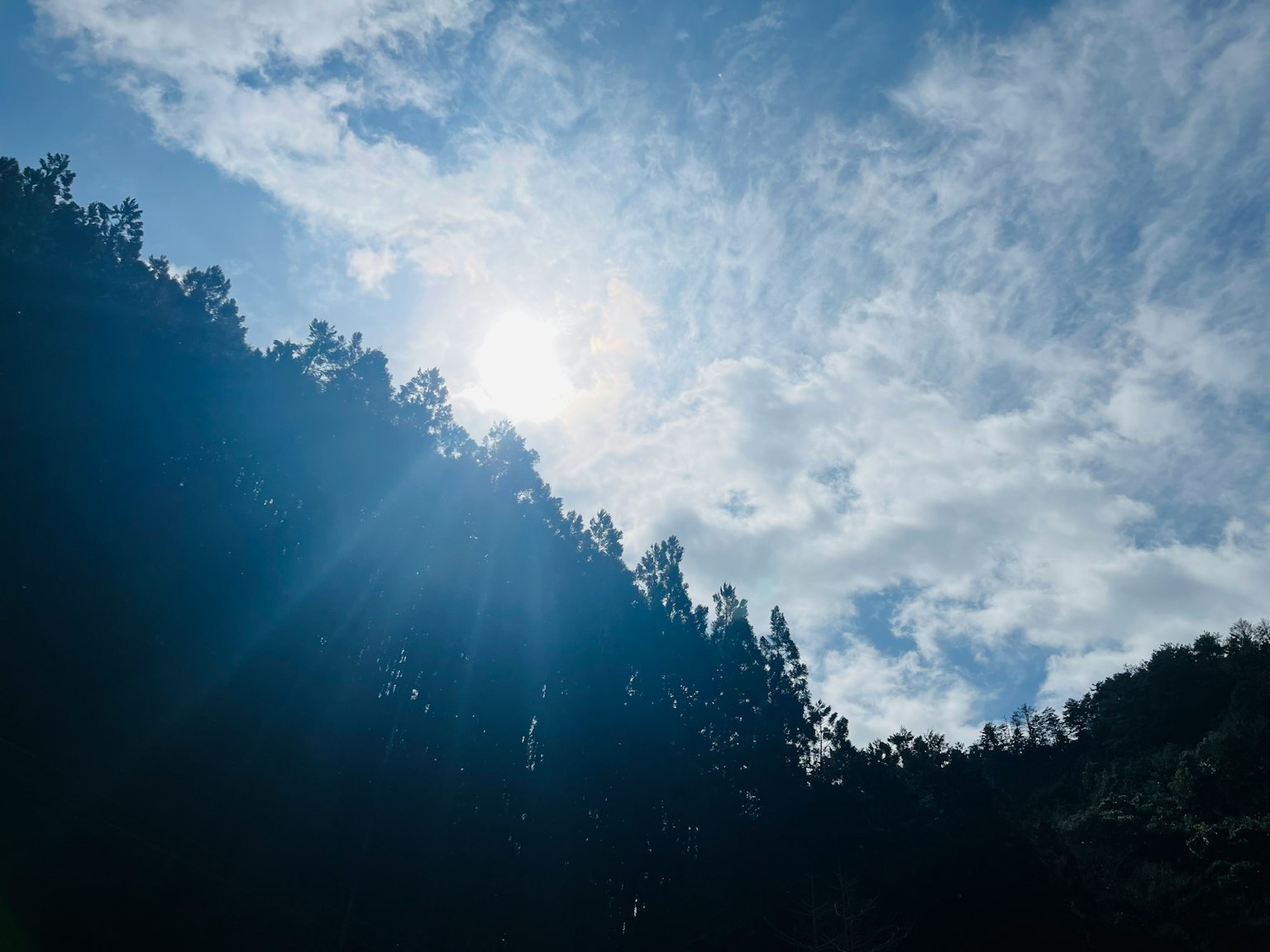 Silhouette di montagne contro un cielo luminoso con nuvole e luce solare