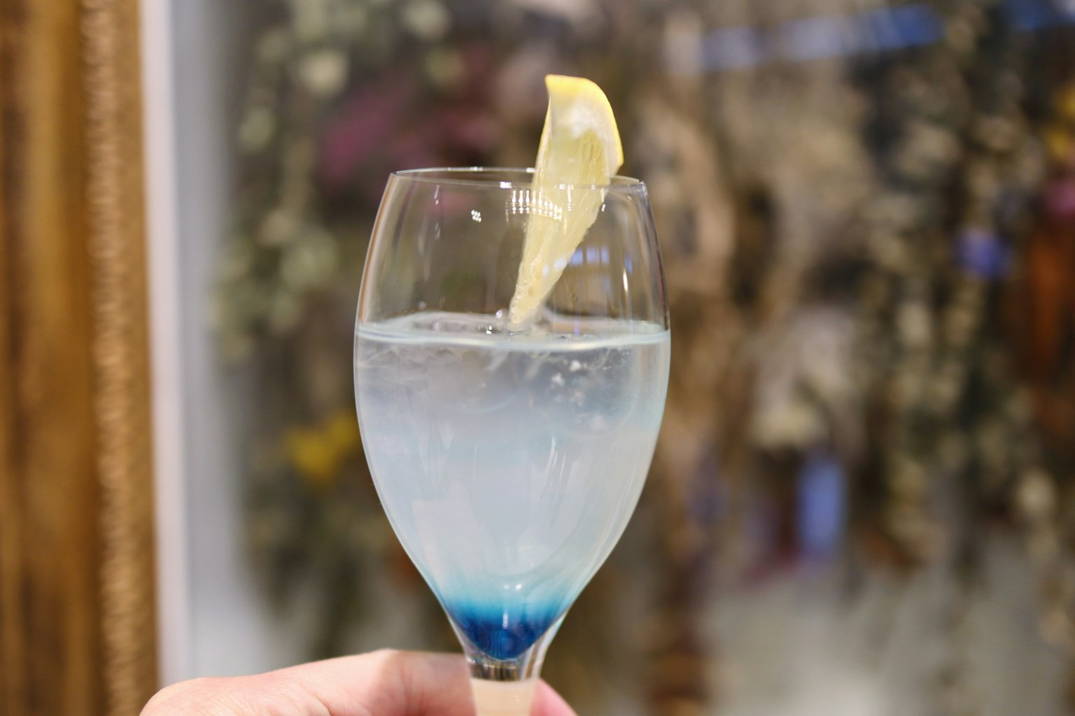 Un vaso transparente con una bebida azul y una rodaja de limón en el borde