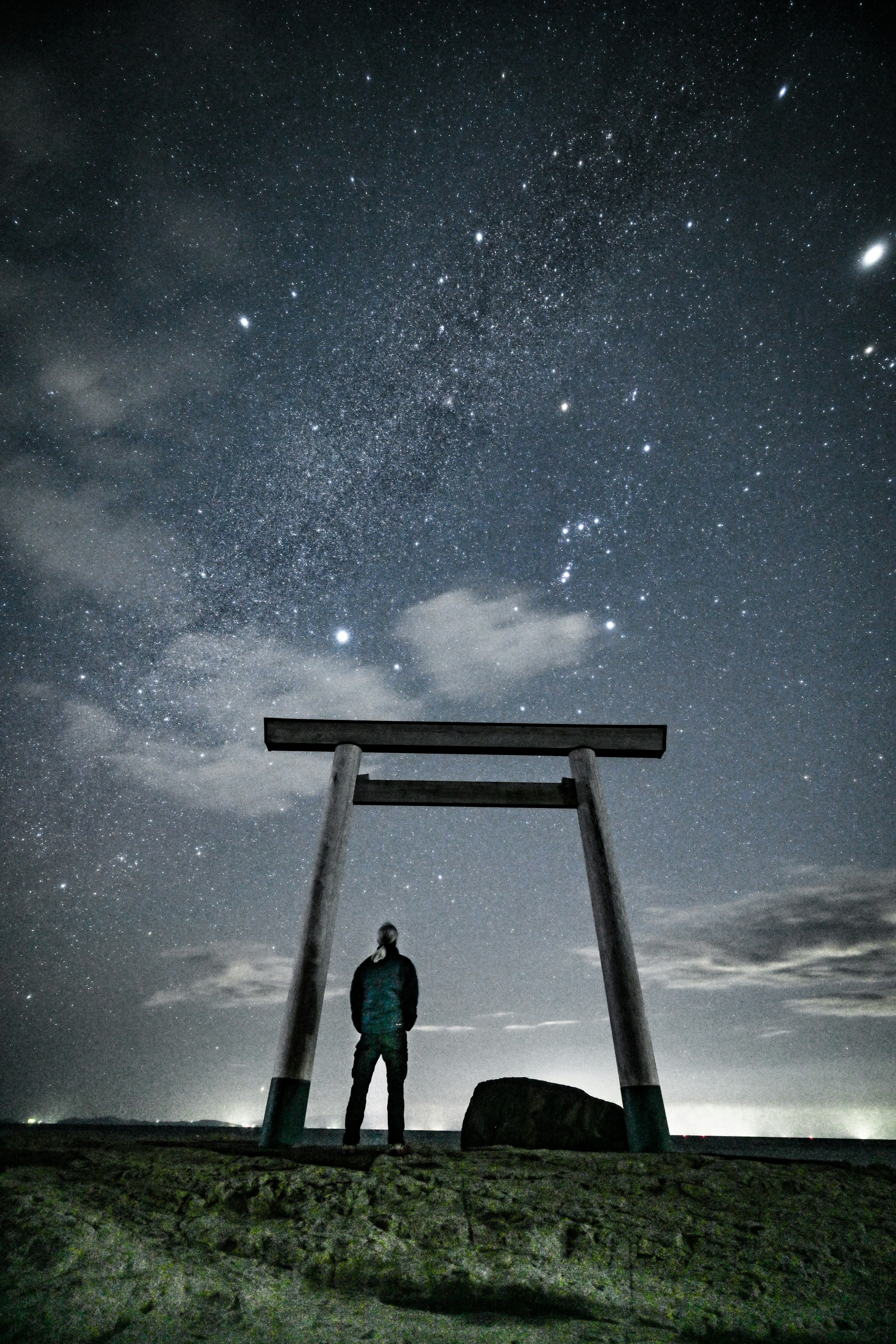 冬の夜空の星と鳥居の前に立つ人物