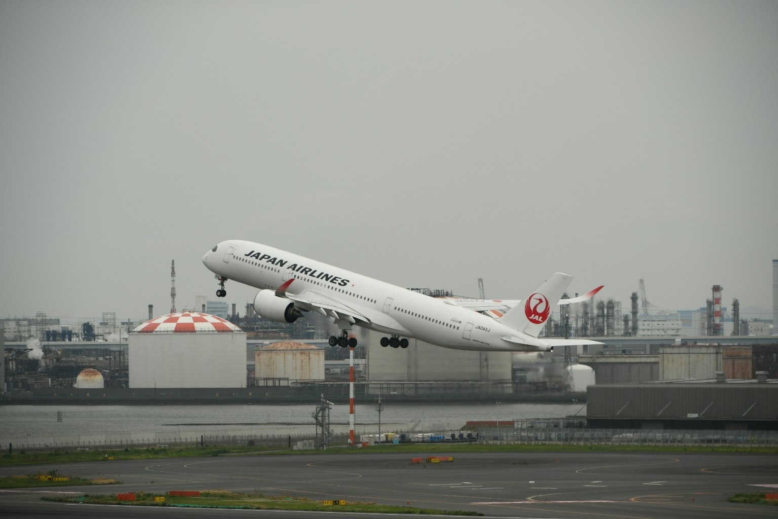 日本航空客机在灰色天空和工业背景下起飞