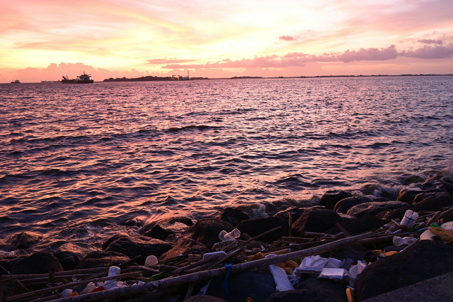 Vista costera con basura en la orilla al atardecer