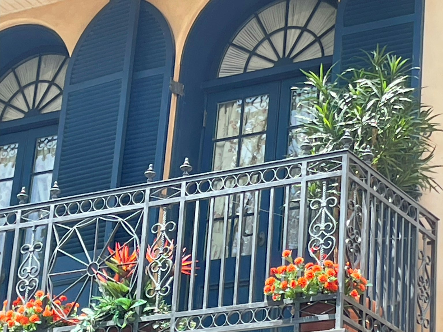 Außenansicht eines Gebäudes mit blauen Fenstern und einem Balkon, der mit Blumen geschmückt ist
