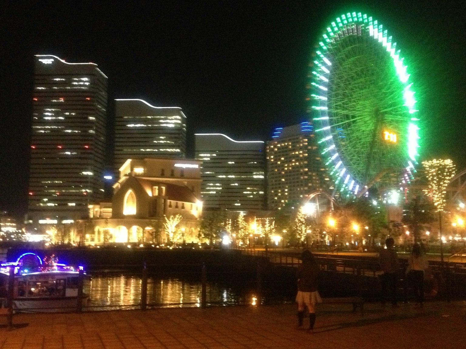 夜景の観覧車とビル群の風景　緑色のライトが輝く
