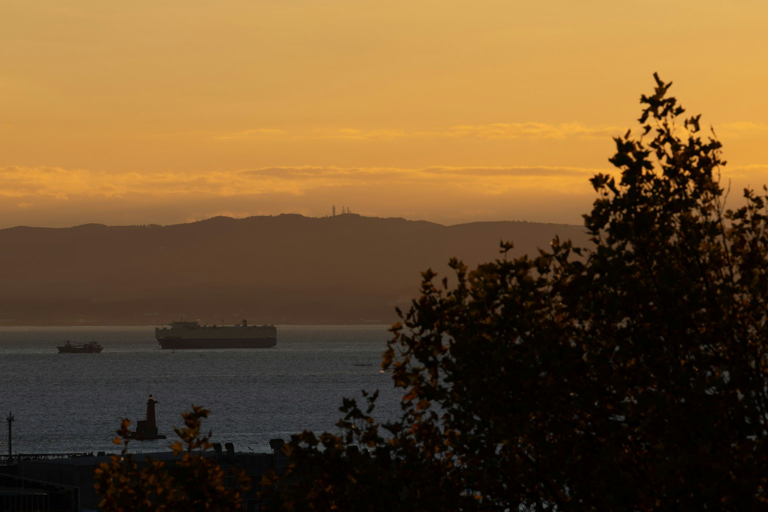 Silueta de barcos de carga en el mar durante el atardecer con montañas al fondo