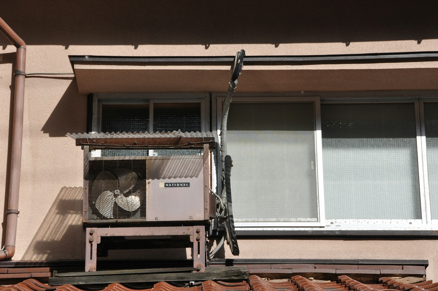 Unità di condizionamento installata all'esterno di una finestra con strutture circostanti