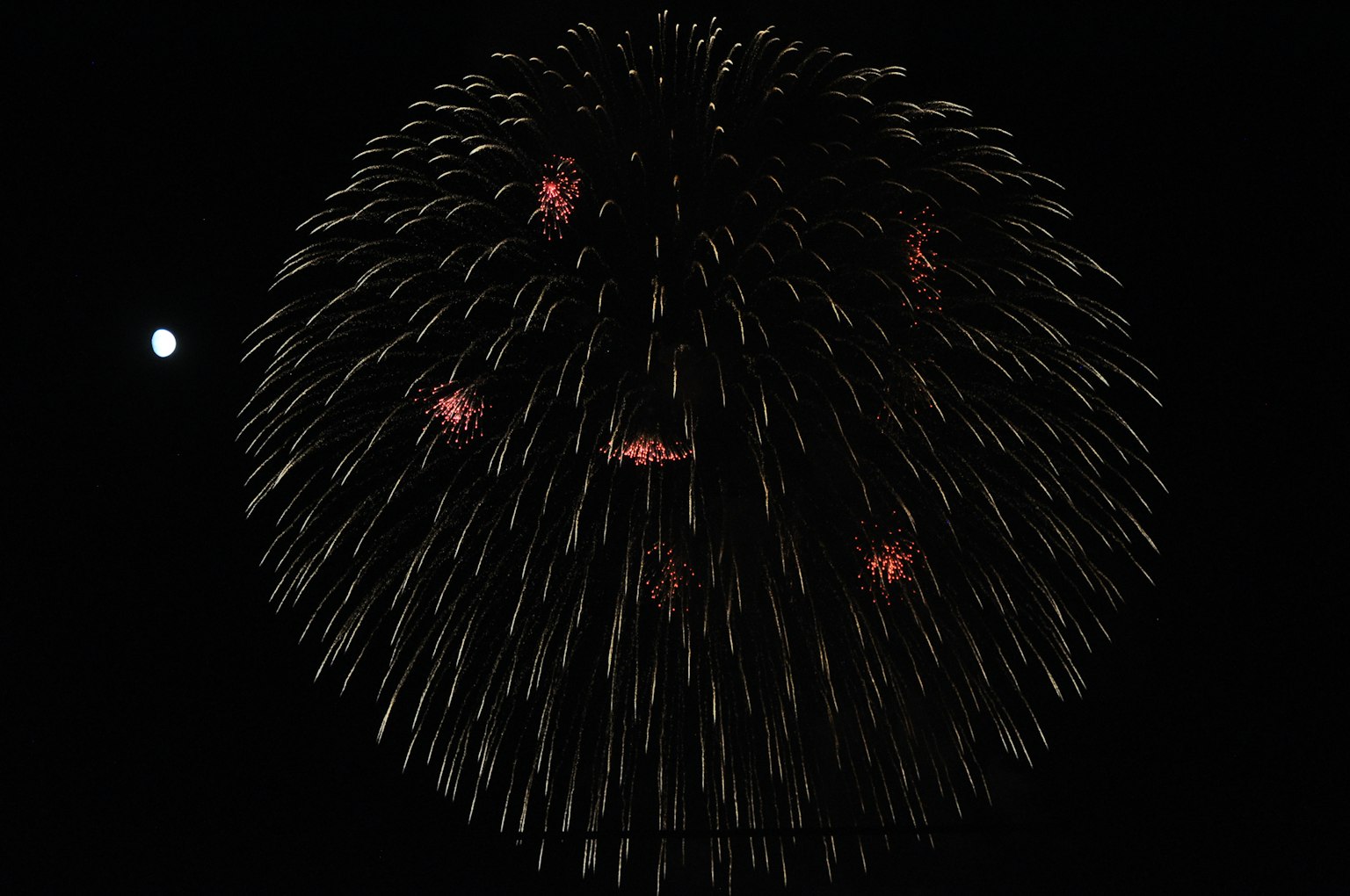 夜空中烟花的球形爆炸与小月亮