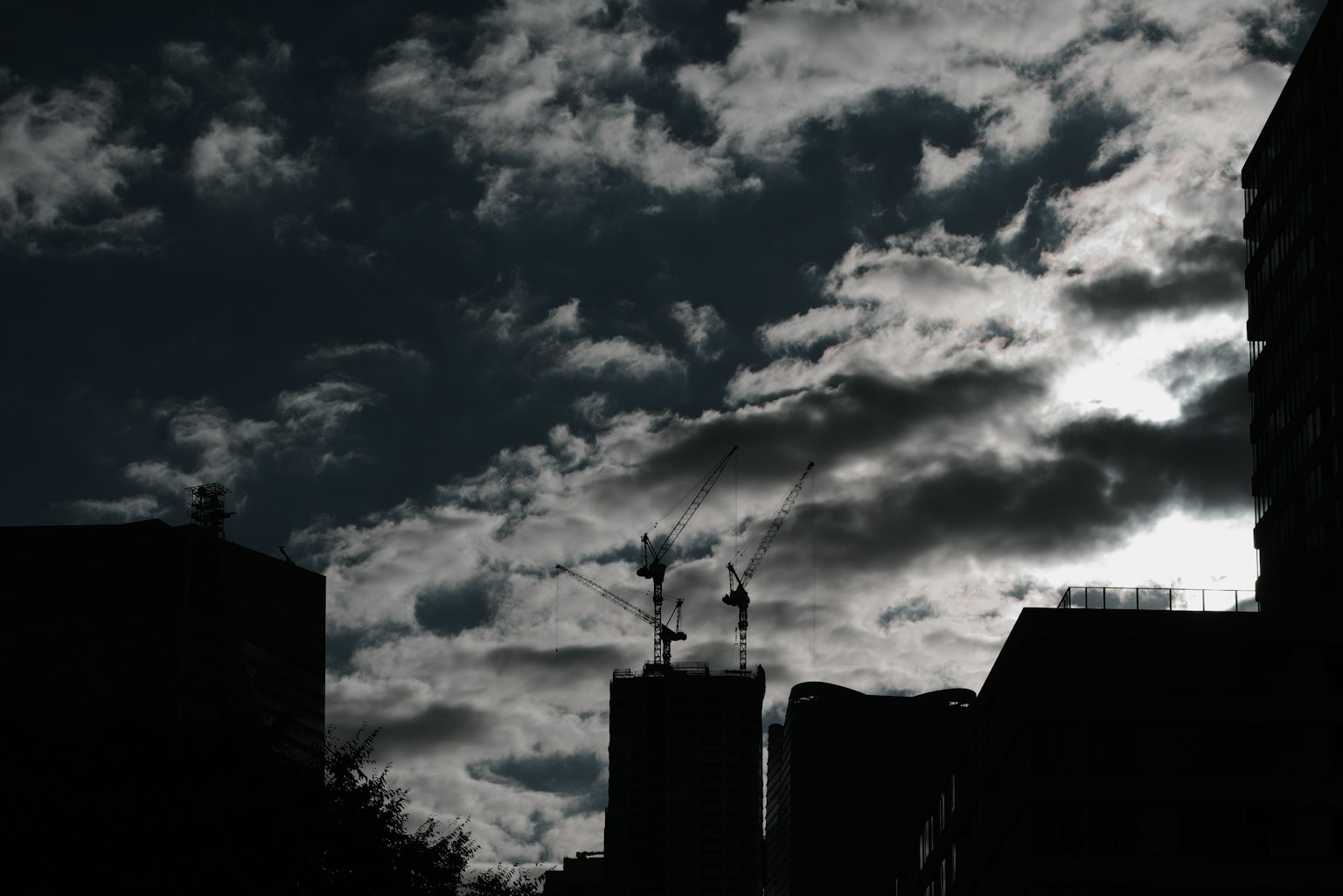 Silhouette bangunan di latar belakang langit gelap penuh awan