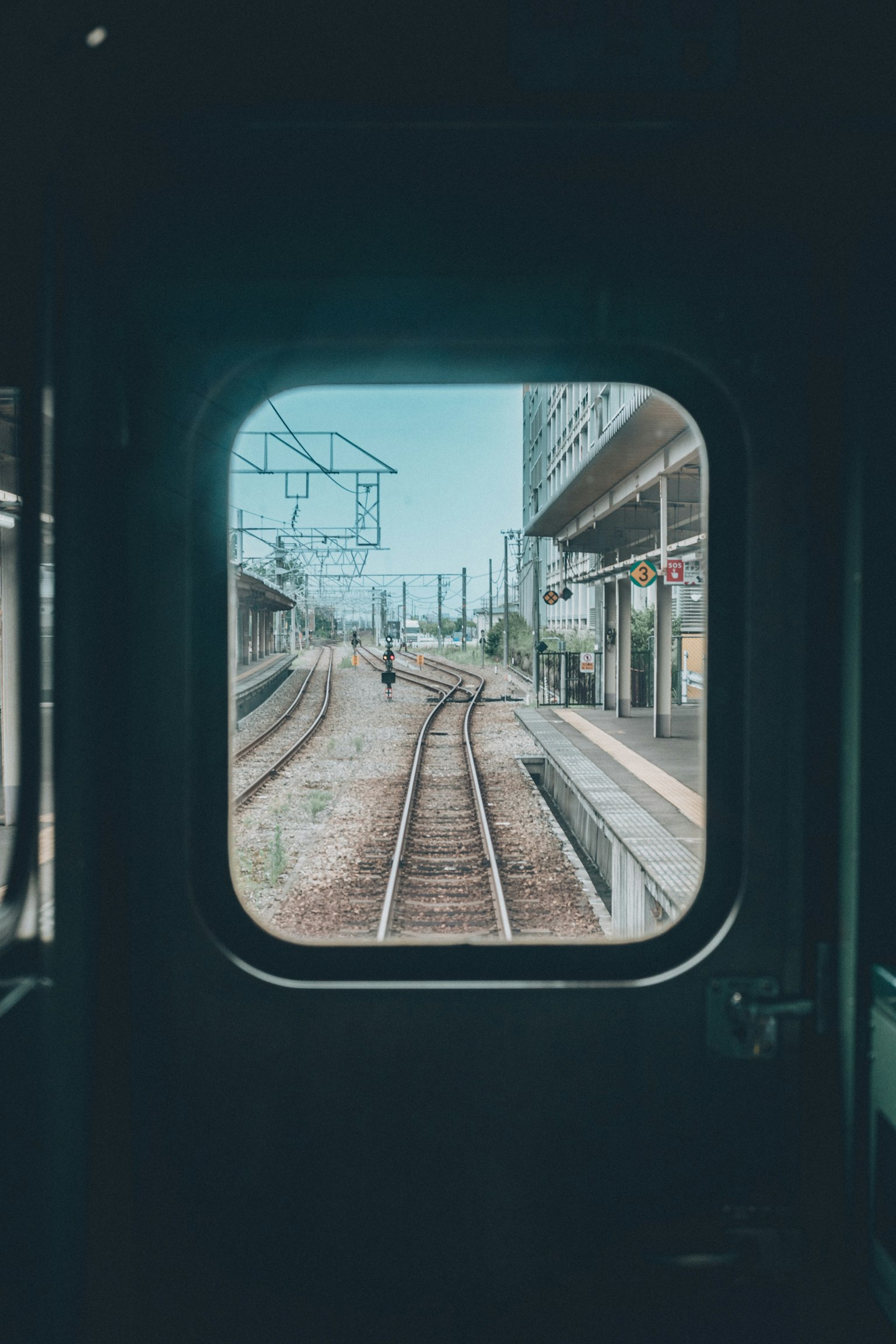 Blick aus einem Zugfenster auf Gleise und Bahnhofstrukturen
