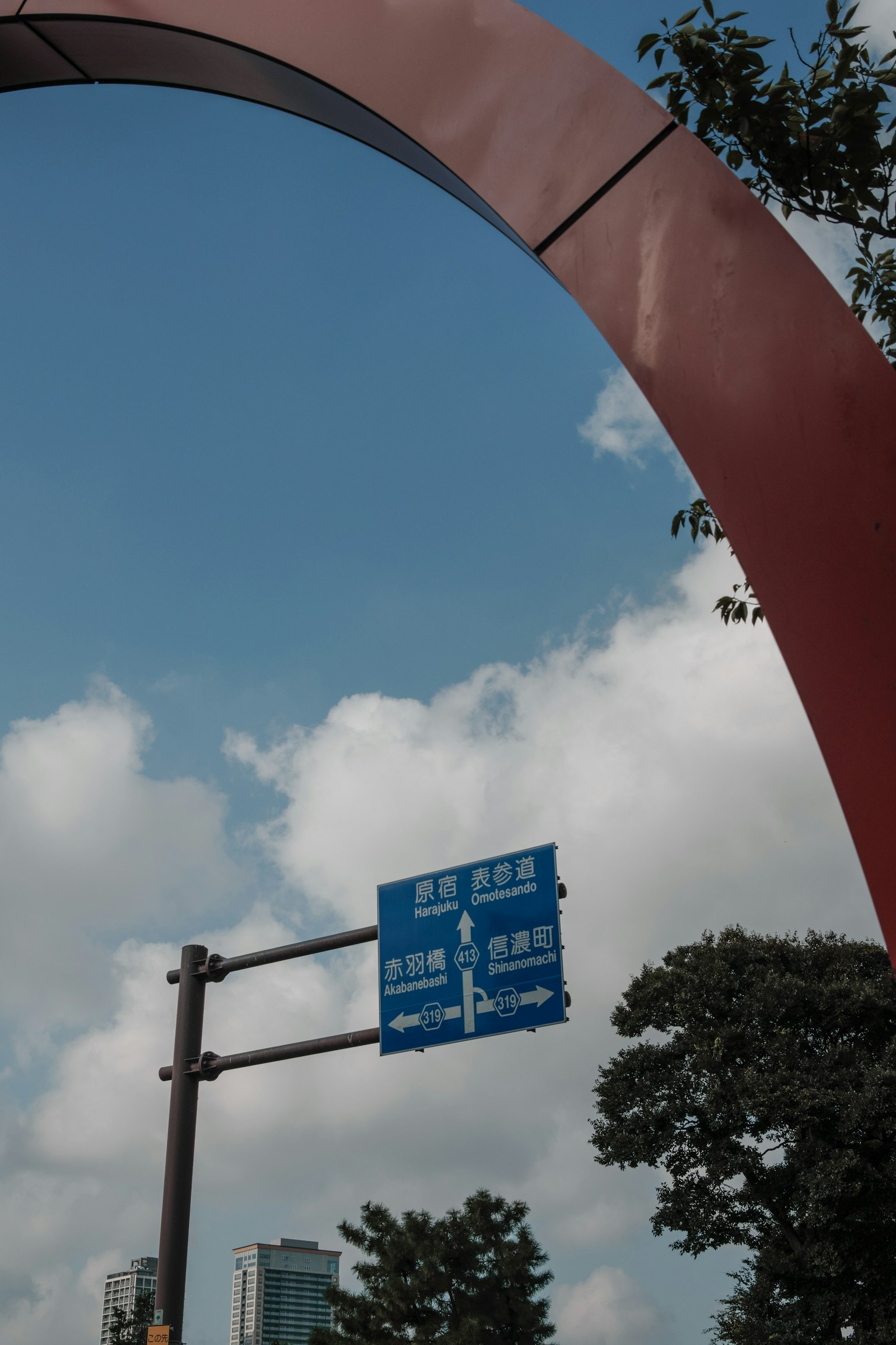 Blue road sign under a red arch with a clear sky