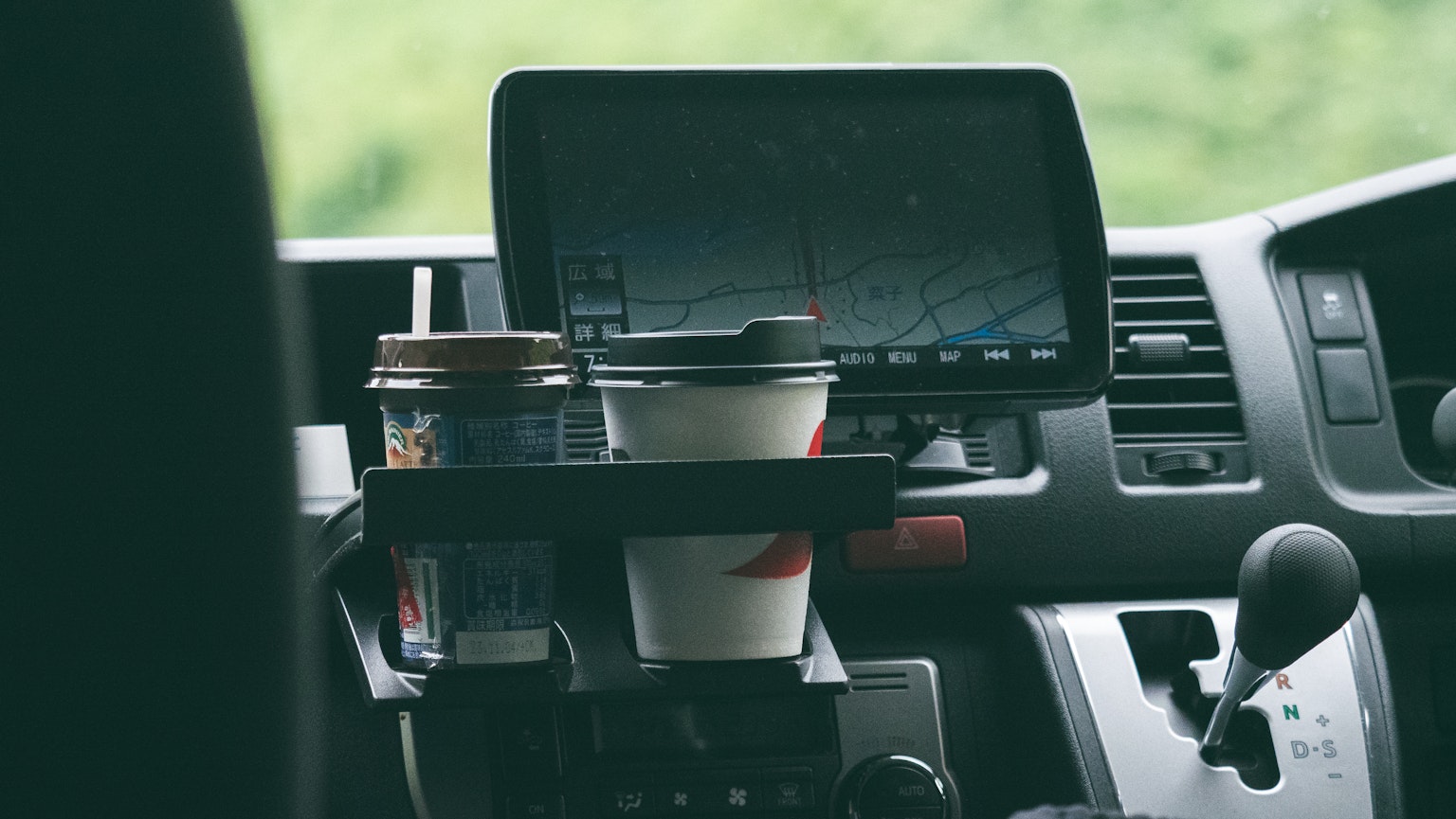 Interno di un veicolo con tazze di caffè in un portabicchieri e un display di navigazione
