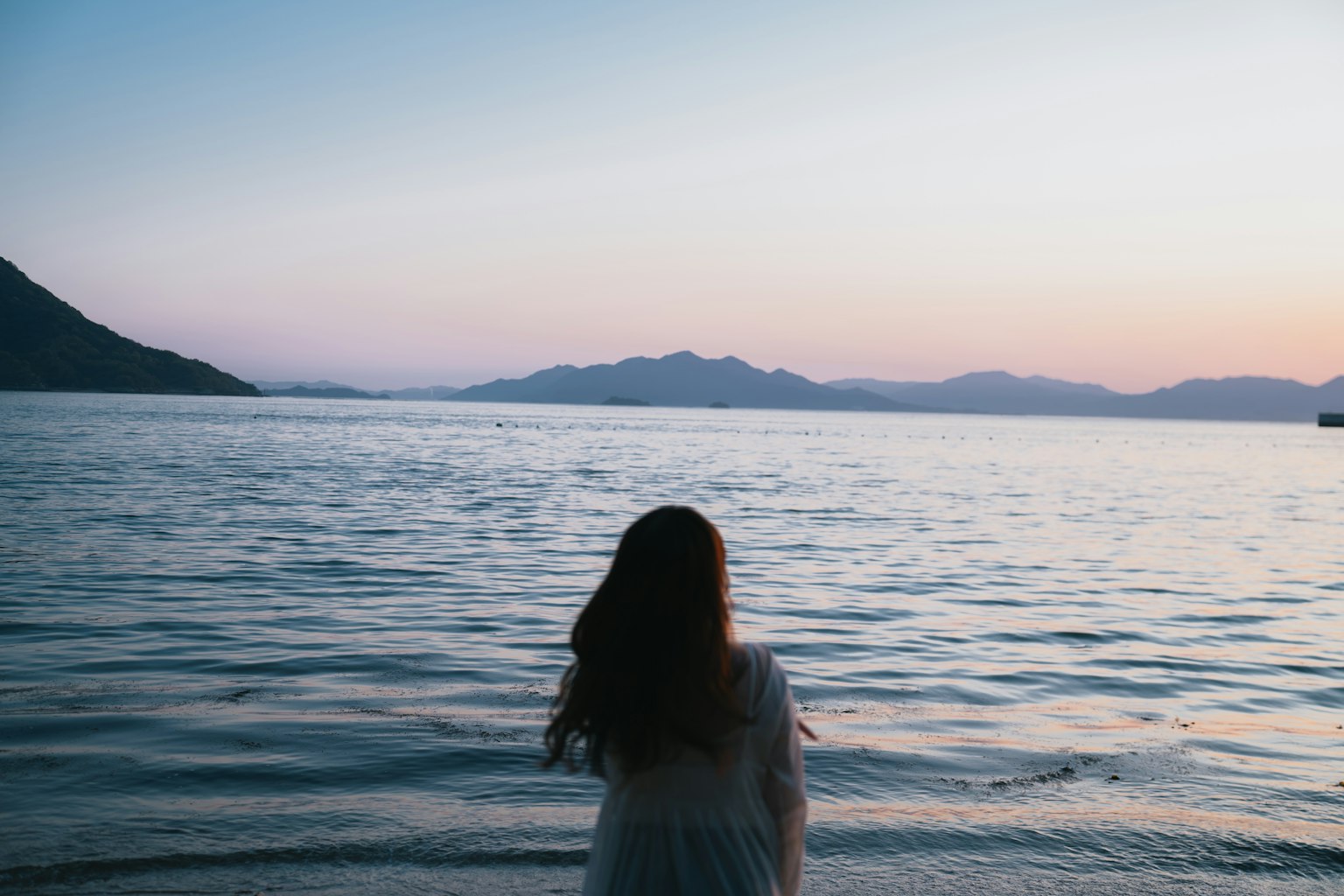 Una donna che guarda il mare al tramonto
