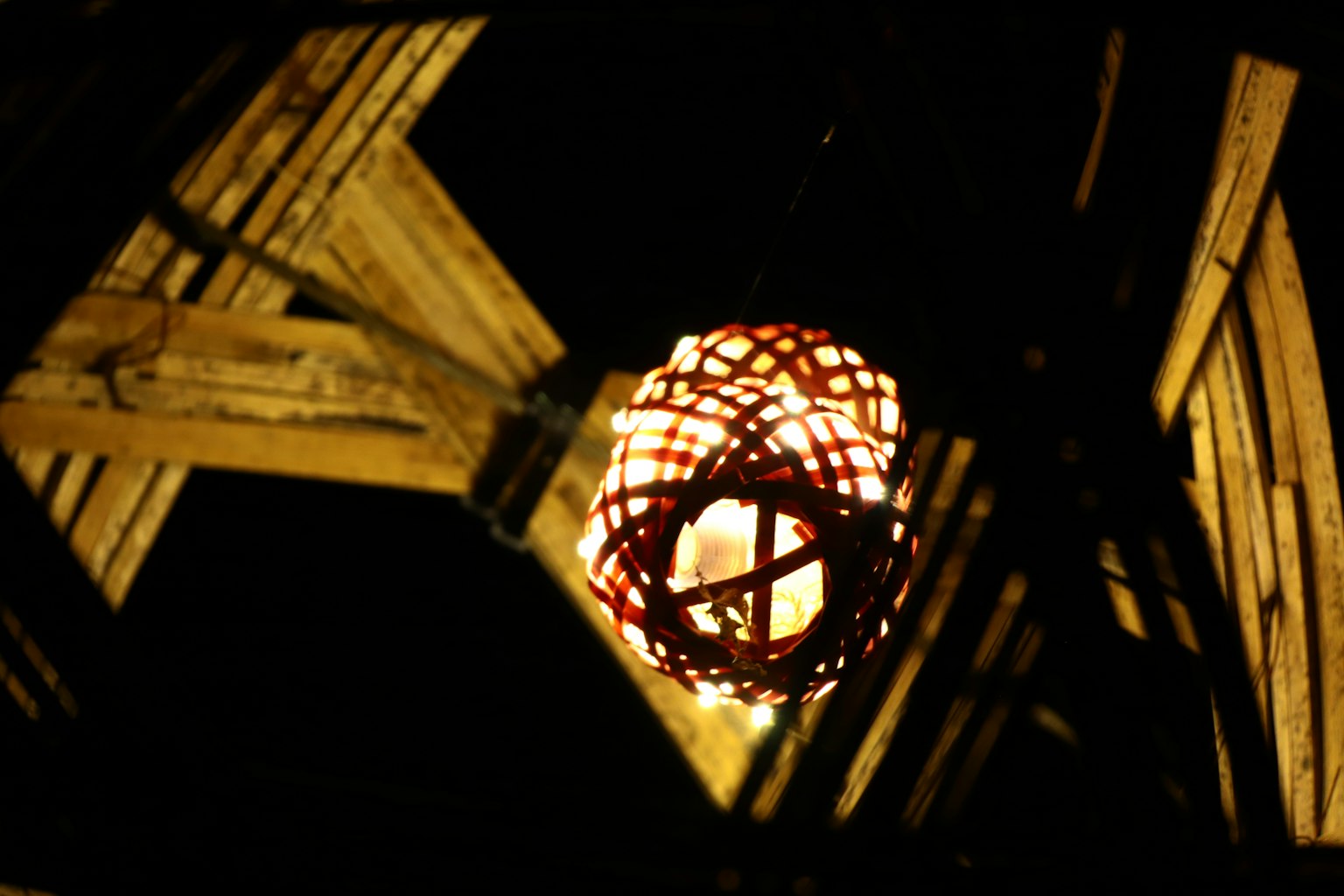 A lantern light hanging between wooden beams illuminating the surroundings