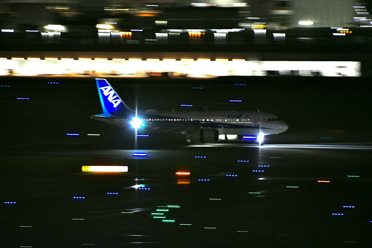 ANA飛機在夜間起飛，明亮的燈光和運動模糊