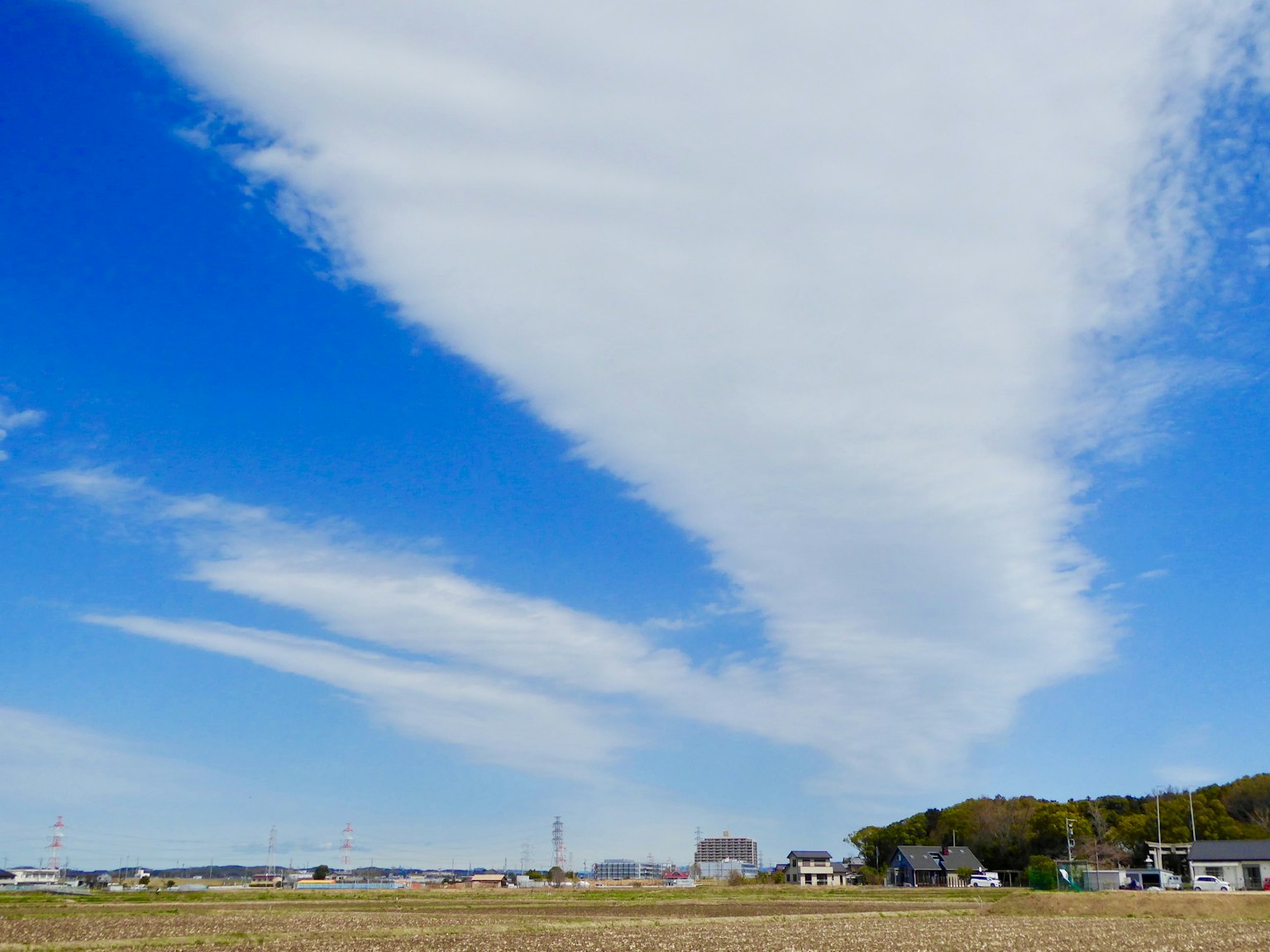 Weitläufiger blauer Himmel mit weißen Wolken und ländlicher Landschaft