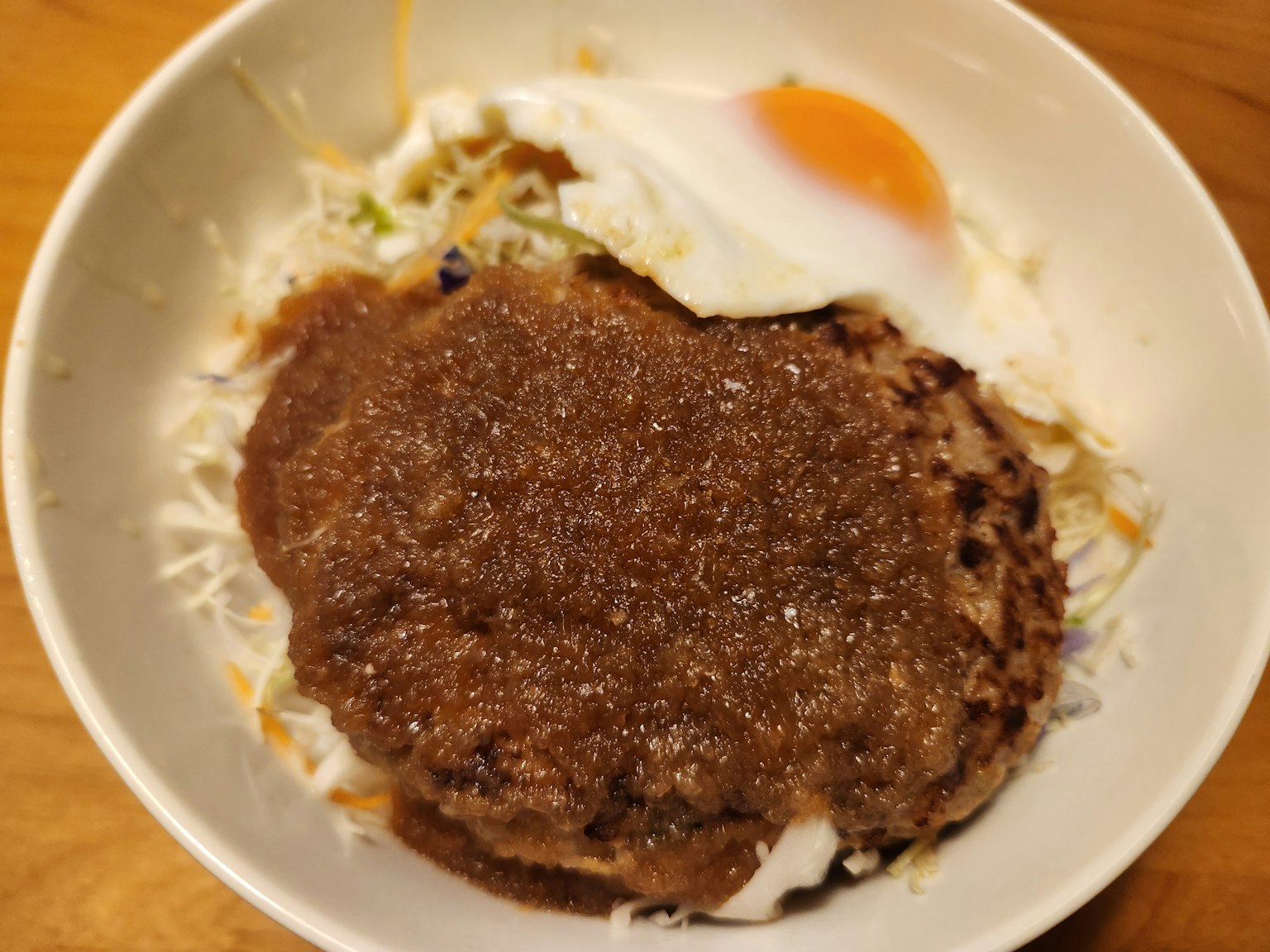 Semangkuk nasi dengan steak hamburger dan telur goreng di atasnya