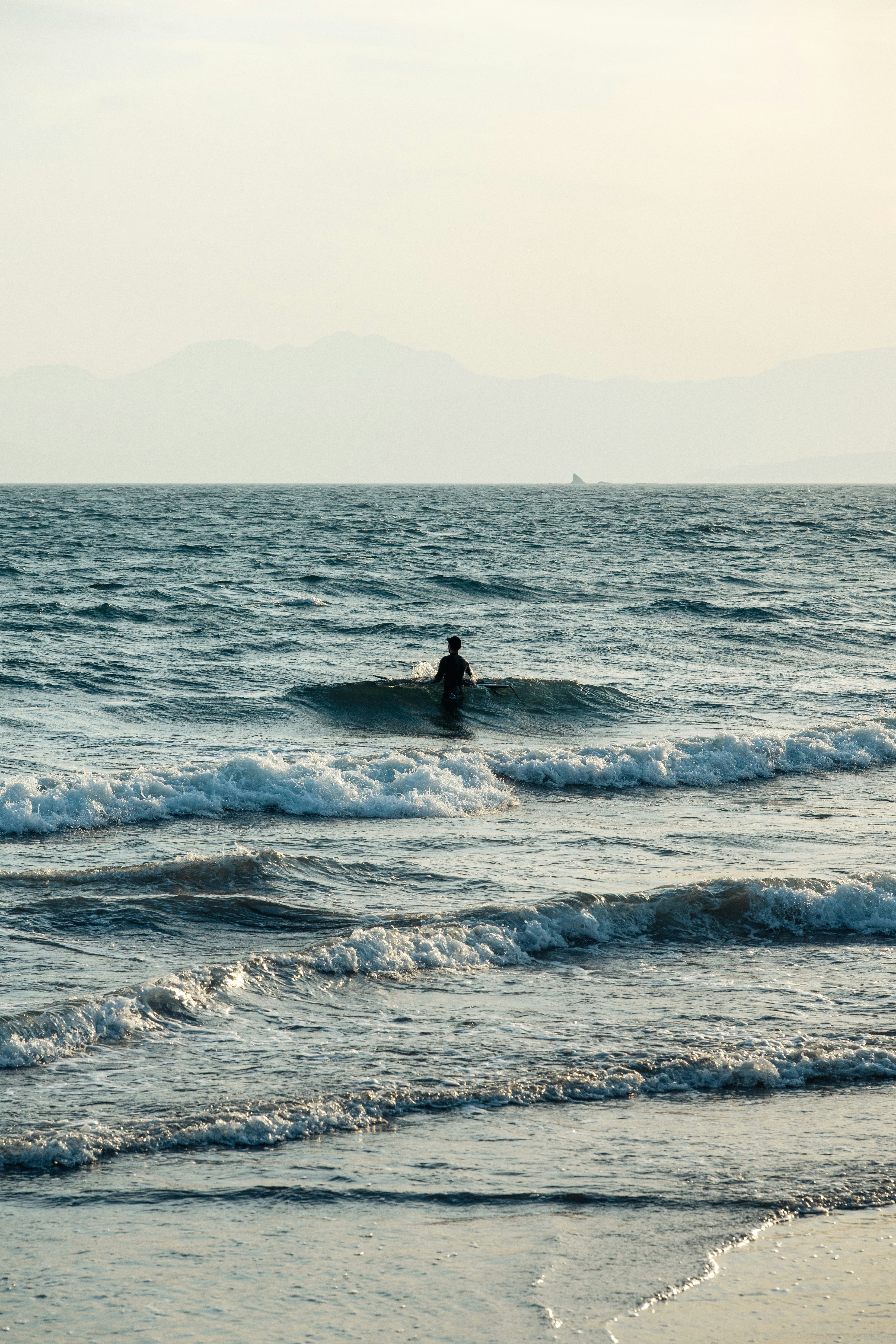 波打ち際で海を見つめる人影のある海辺の風景