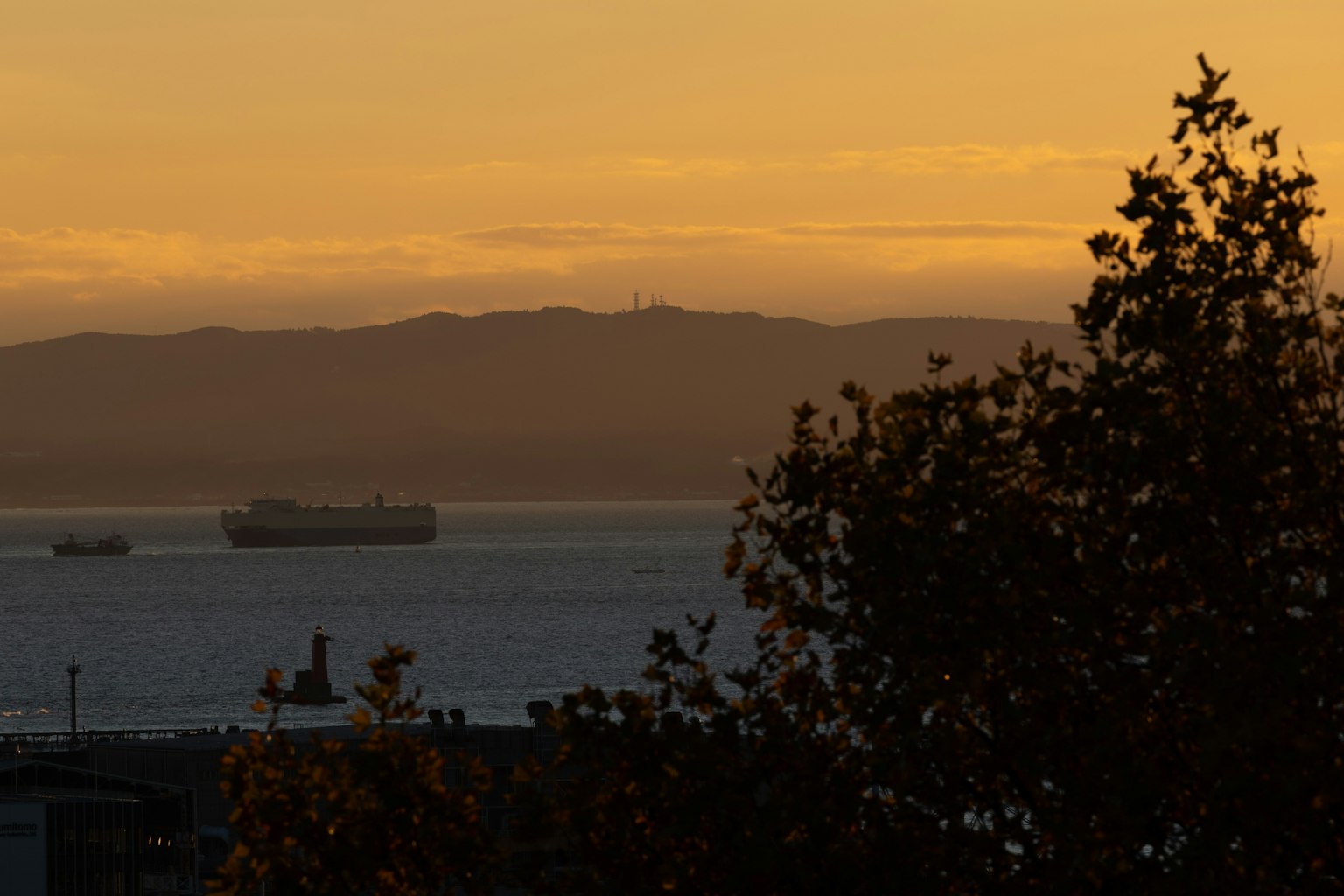 Silueta de barcos de carga en el océano con montañas al atardecer