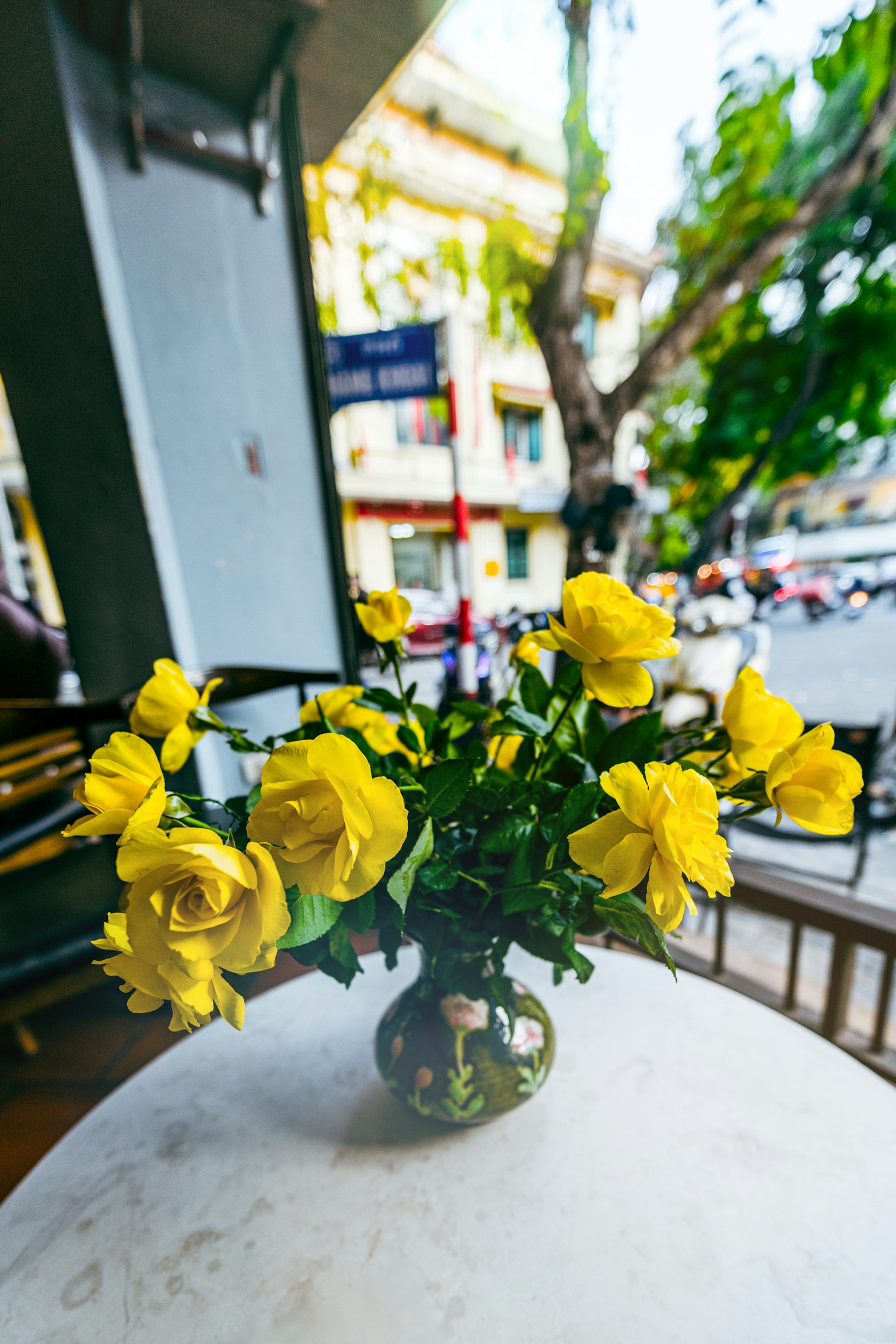 Ein Strauß gelber Rosen auf einem Tisch mit Stadtansicht im Hintergrund