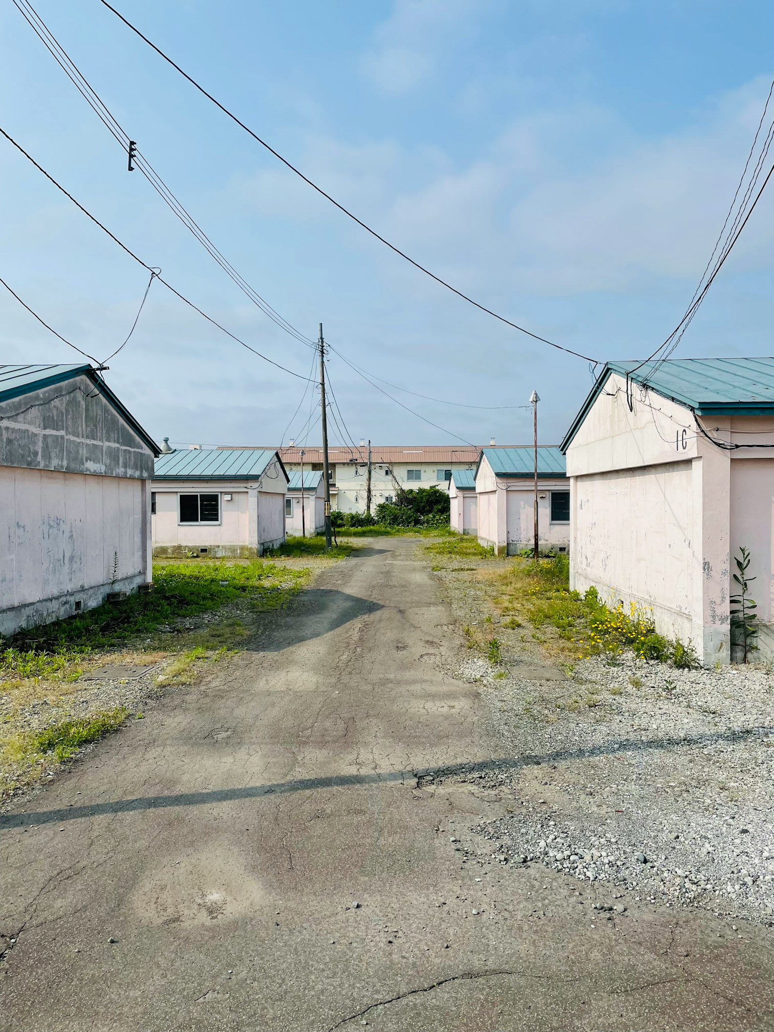 View of white buildings with blue roofs along a gravel path