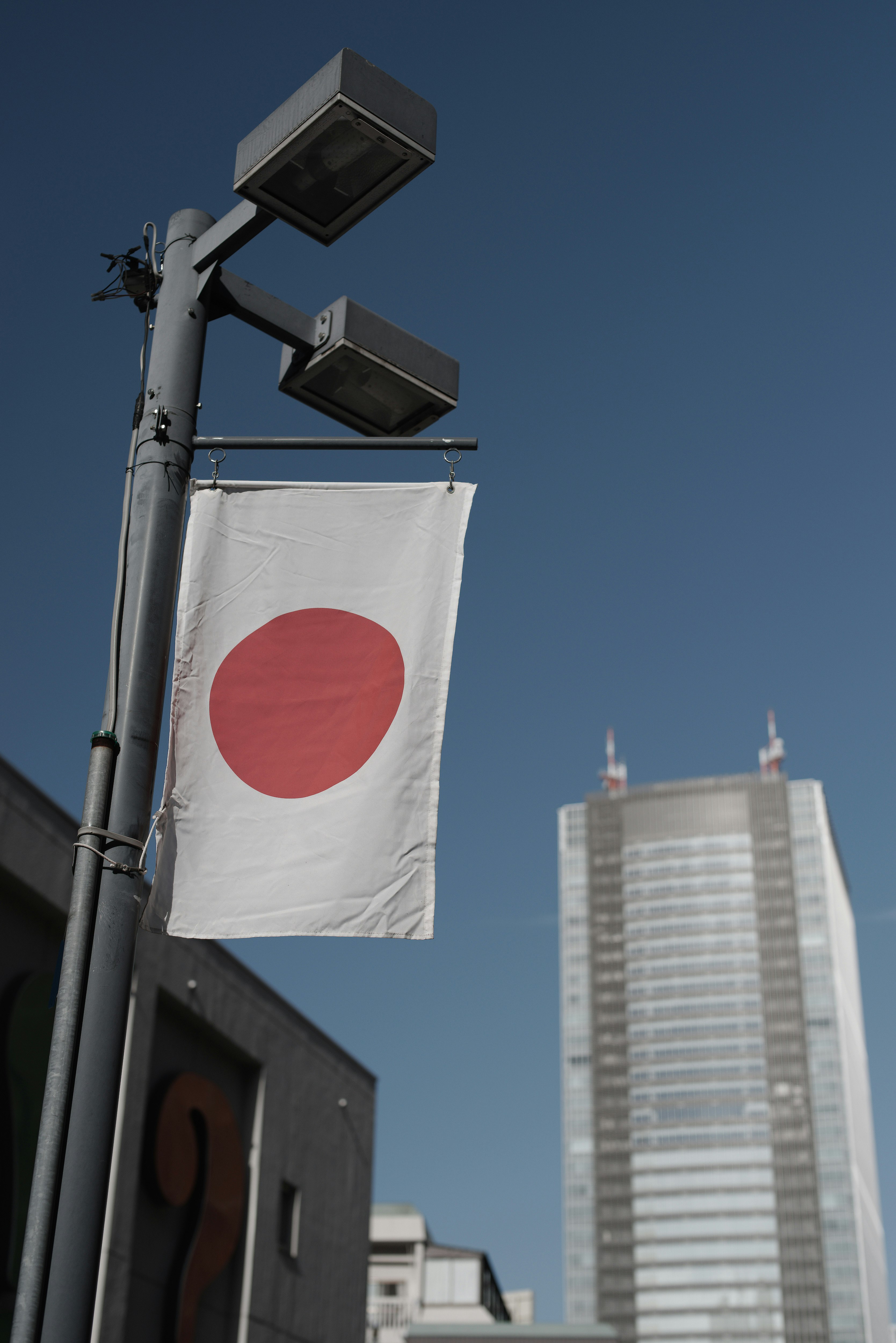 青空の下で掲げられた日本国旗と東京の高層ビル群